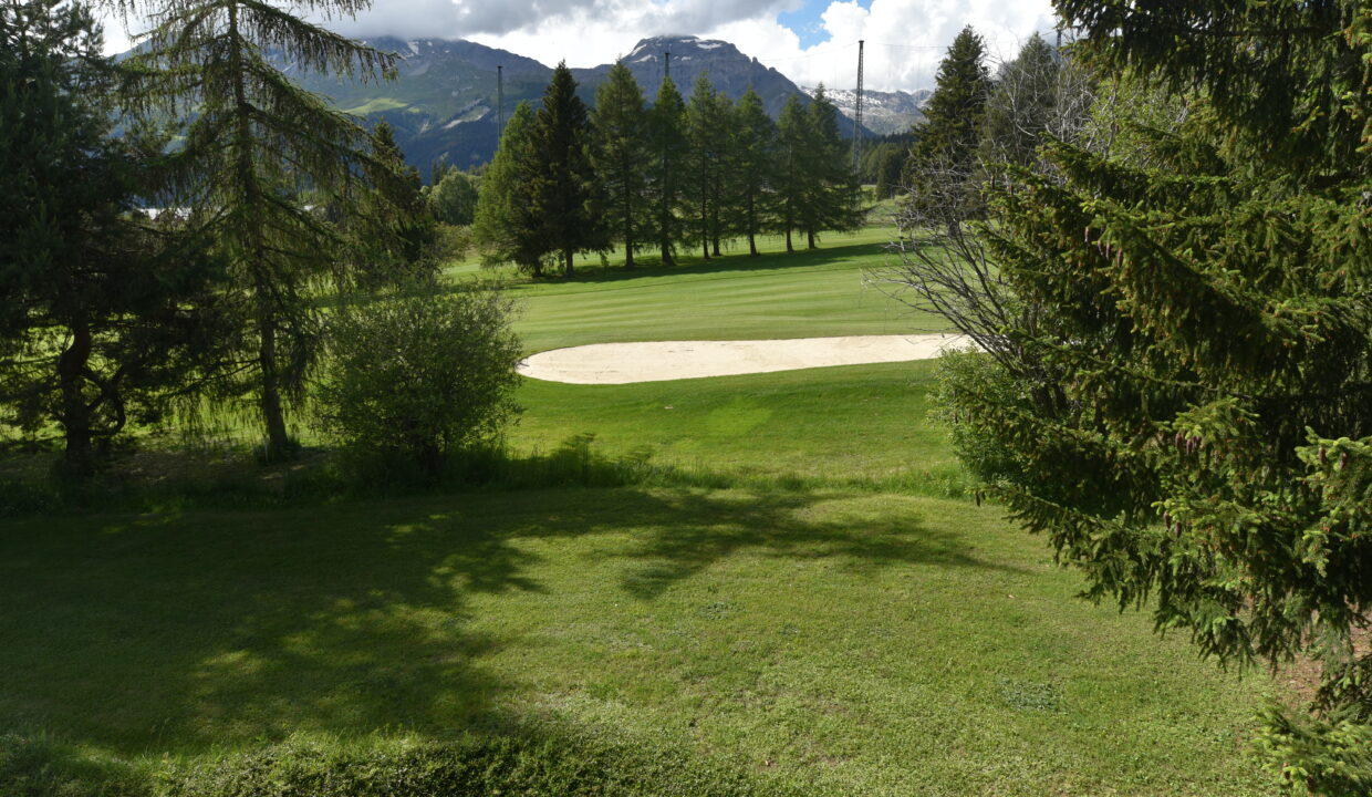 Blick über eine grüne Golfanlage mit Bergkulisse