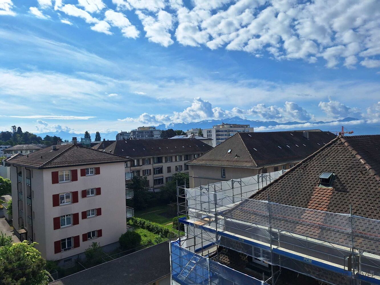 Blick über Wohnhäuser mit Bergen im Hintergrund