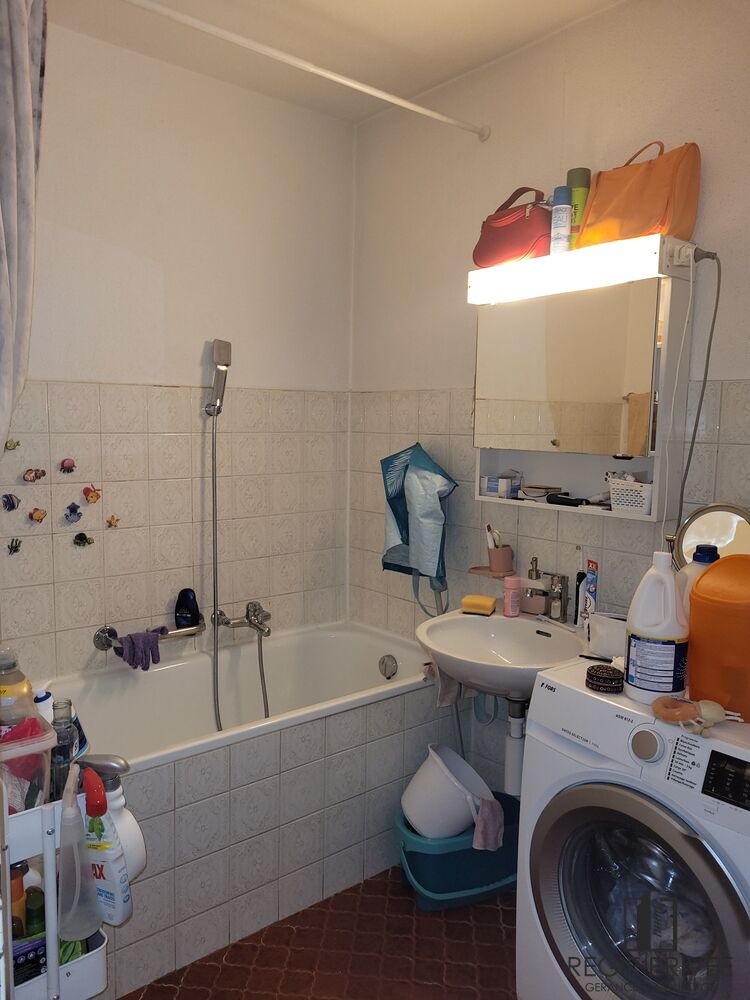 Kleines Badezimmer mit Badewanne, Waschbecken und Waschmaschine