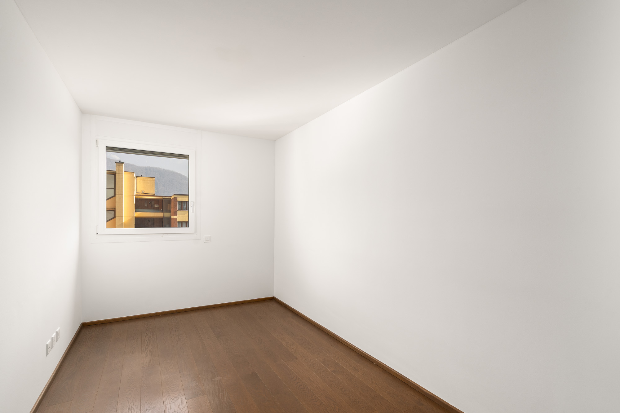 Leerer heller Raum mit Fenster und Holzboden