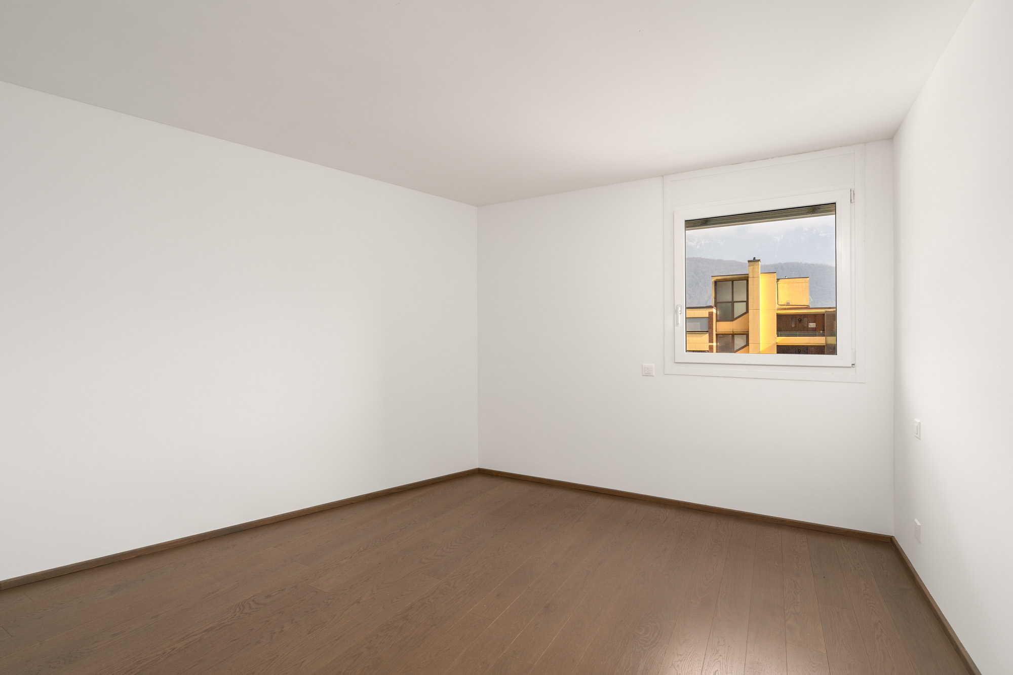 Leerer, heller Raum mit Holzfußboden und Fensterblick
