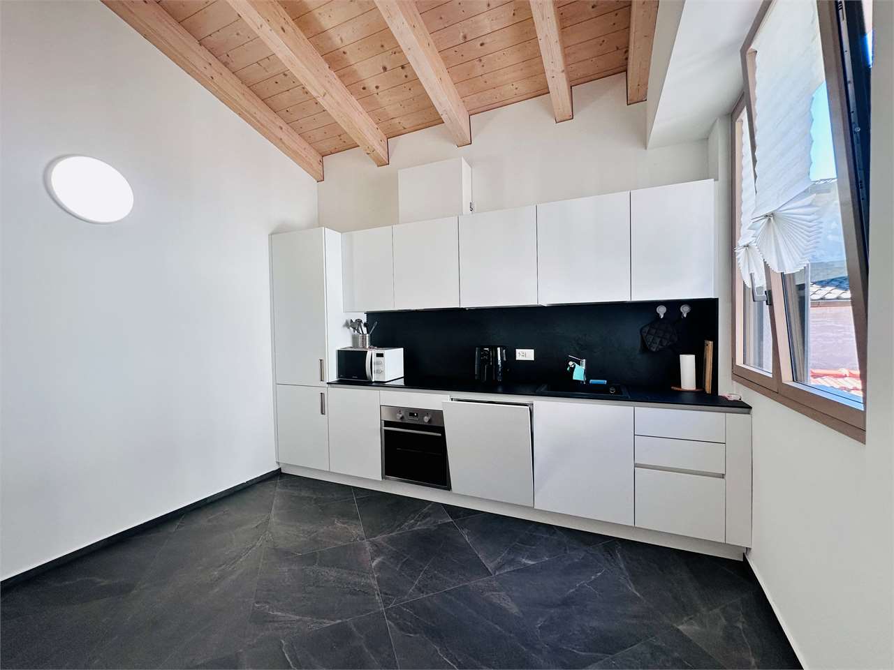 Moderne Küche mit hellem Holzdeckenelement und dunklem Boden