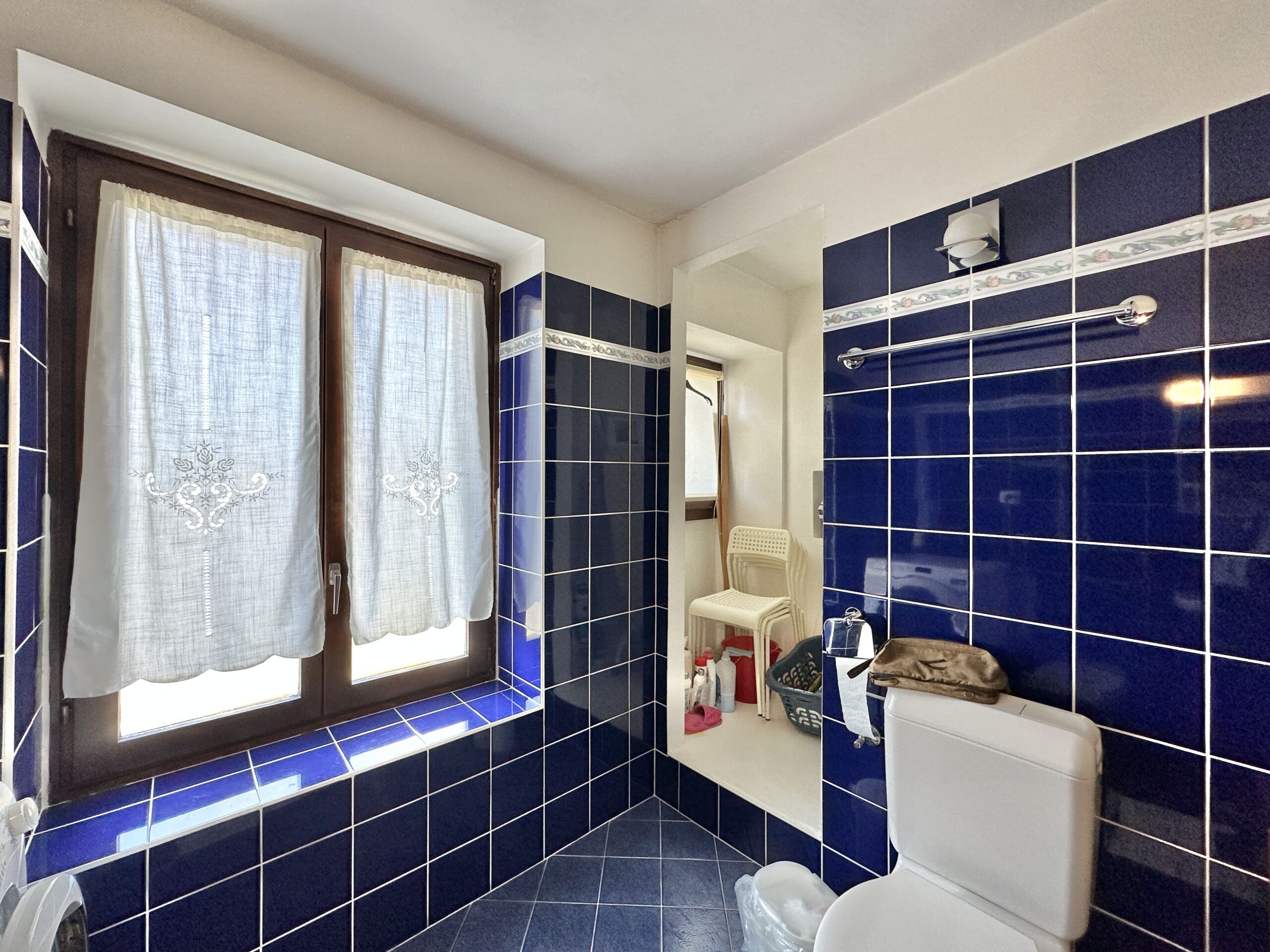 Badezimmer mit blau gefliesten Wänden und Fenster