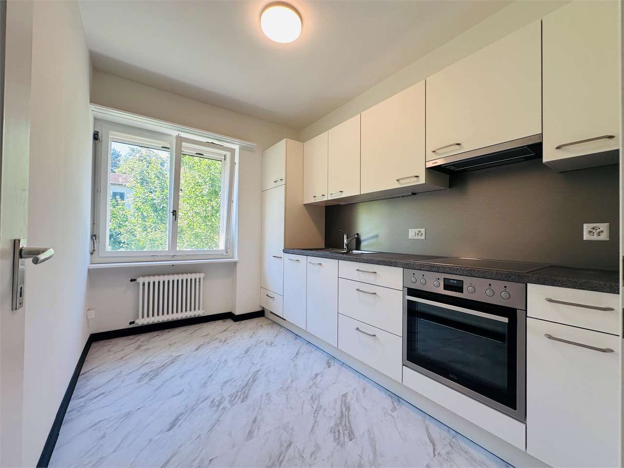 Helle, moderne Küche mit Fenster und Einbaugeräten