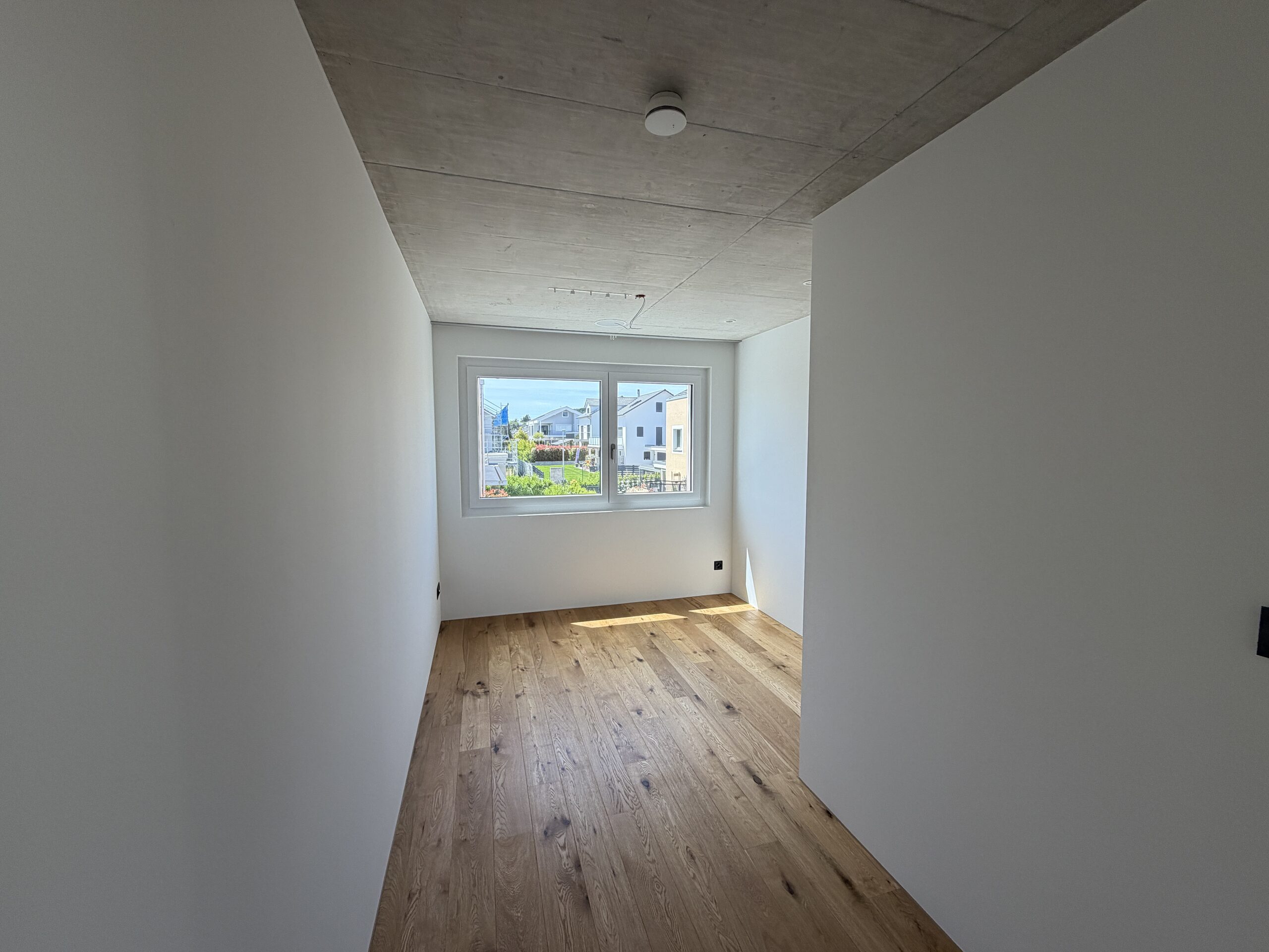 Heller leerer Raum mit Holzfußboden und Fensterblick