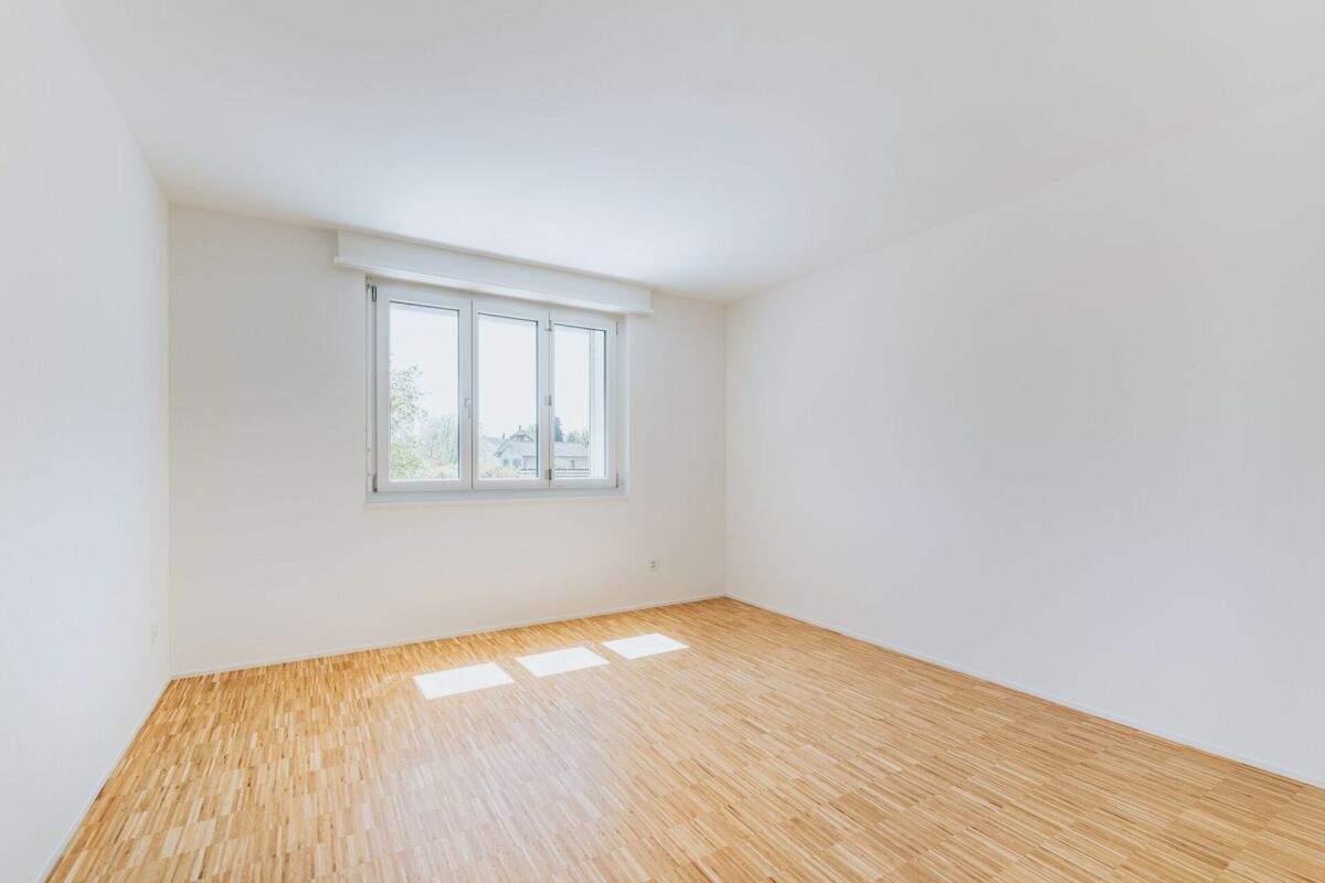 Heller leerer Raum mit Holzfußboden und Fenster