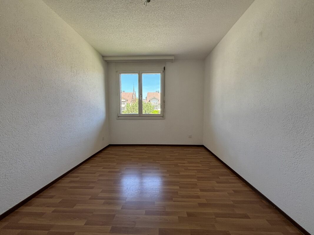 Leeres Zimmer mit Fenster und Holzoptik-Boden