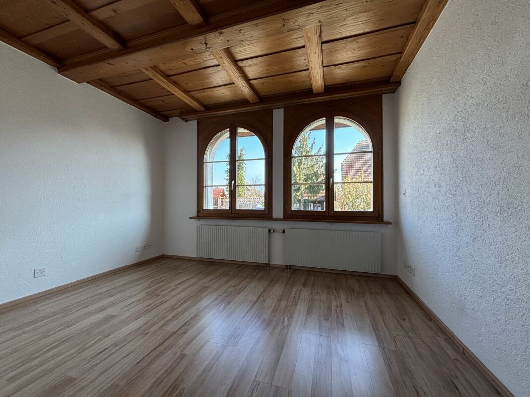 Leerer Raum mit Holzbalkendecke und Rundbogenfenstern