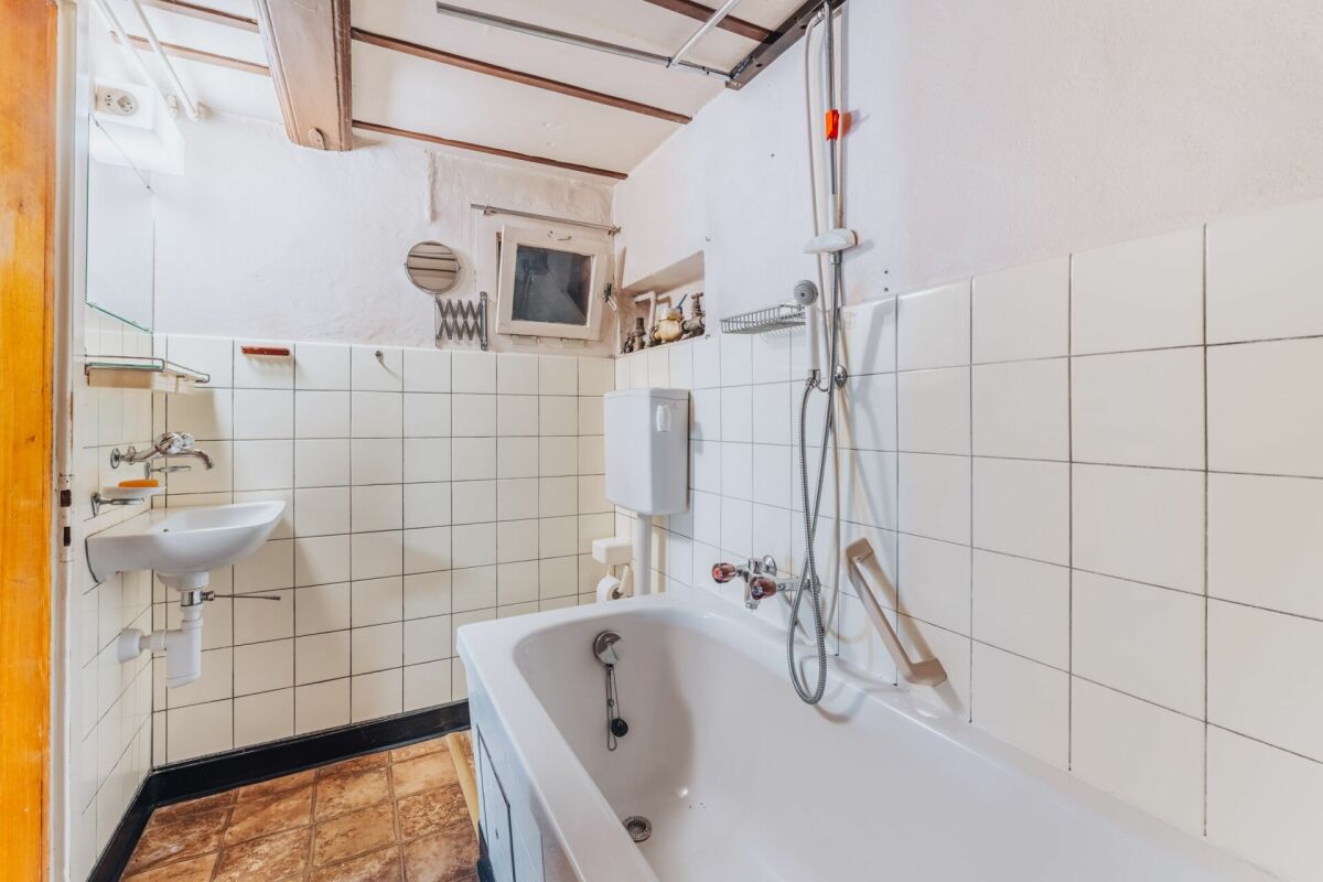 Kleines, schlichtes Bad mit Badewanne und Waschbecken