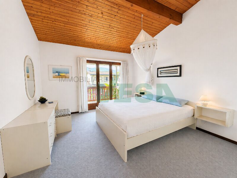 Helles Schlafzimmer mit Holzdecke und Balkonzugang