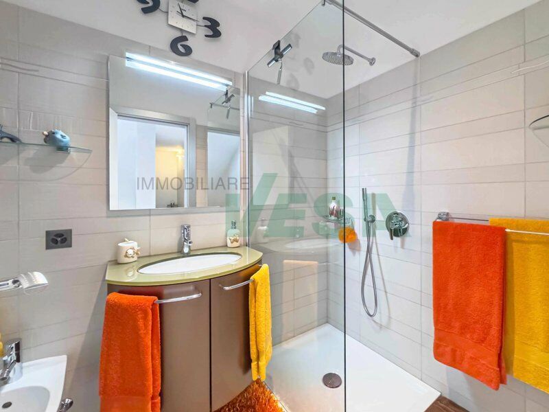 Modernes Badezimmer mit Glasdusche und farbigen Handtüchern