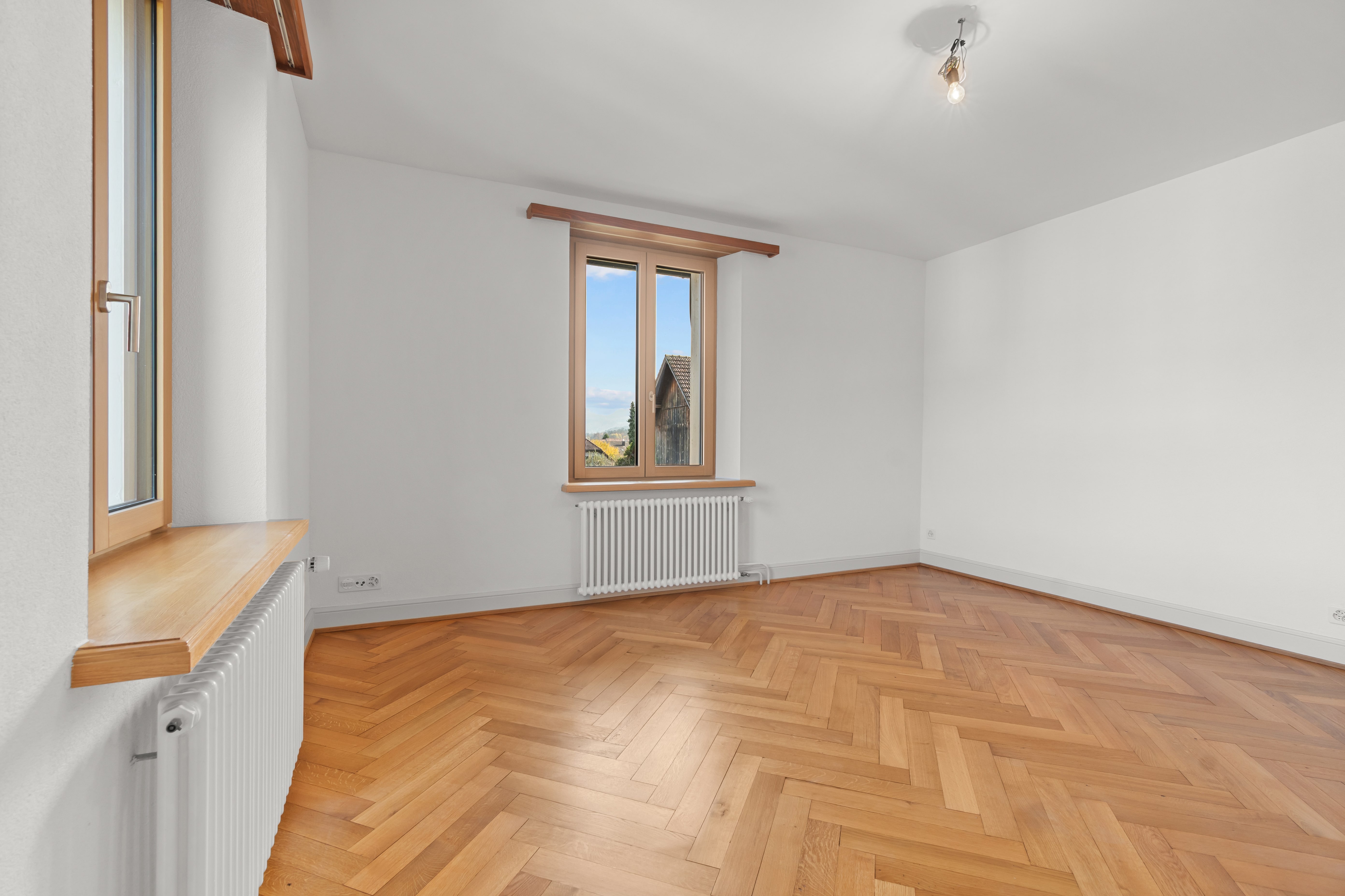 Leerer heller Raum mit Parkett und Fenstern