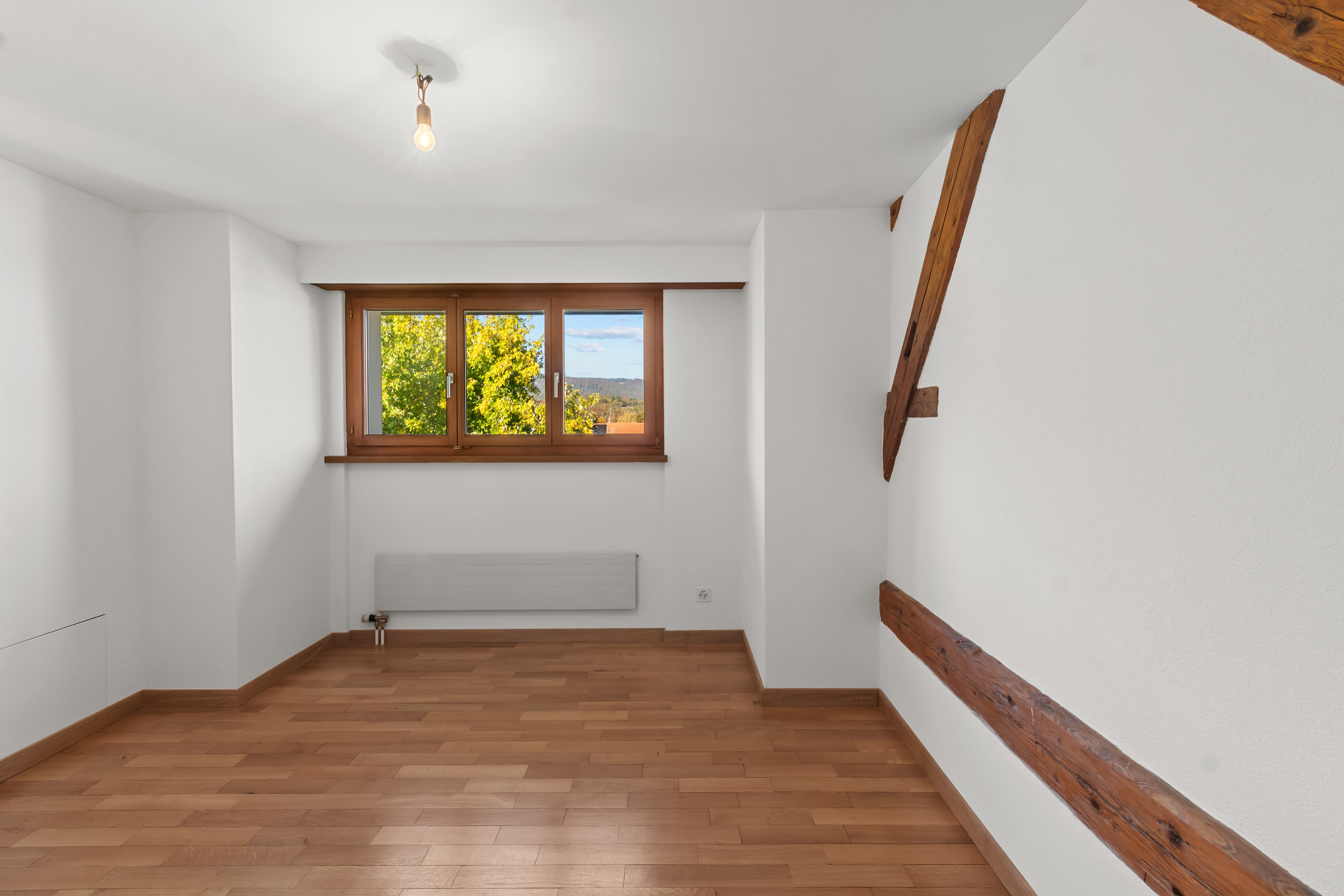 Leerer Dachraum mit Holzfenster und Parkett