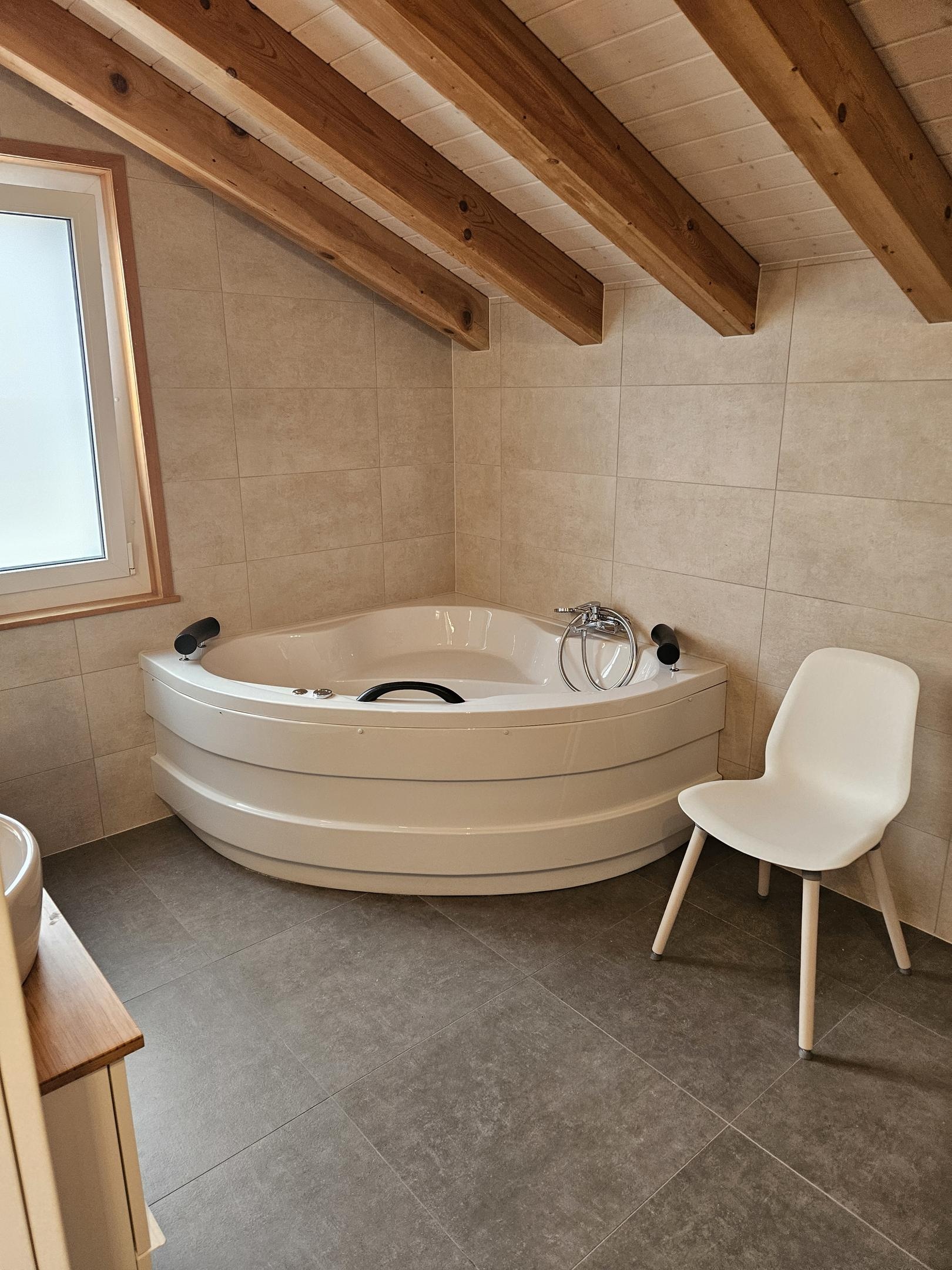 Badezimmer mit Eckwanne und Holzdeckenbalken