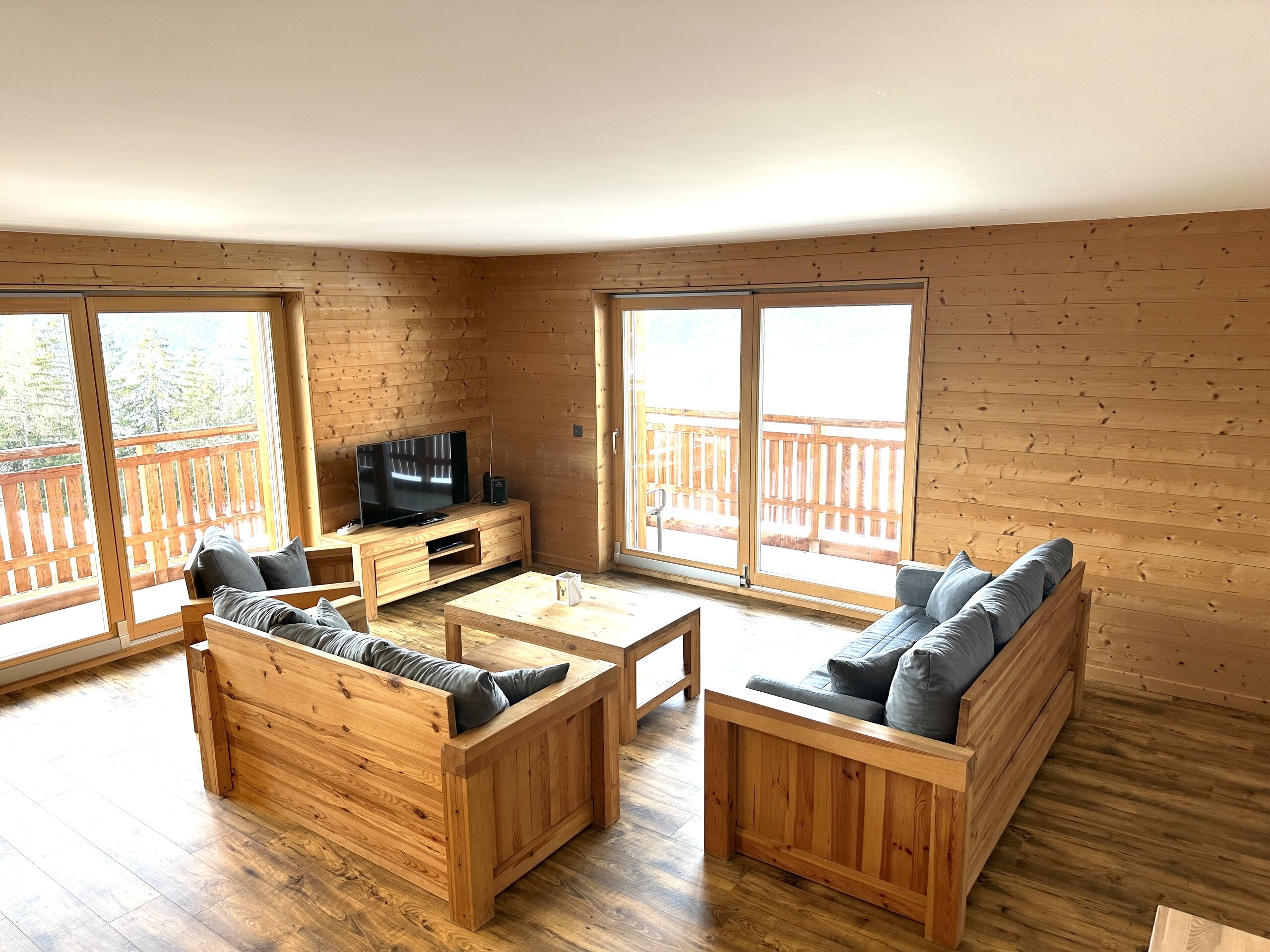 Helles Wohnzimmer mit Holzverkleidung und Balkonblick