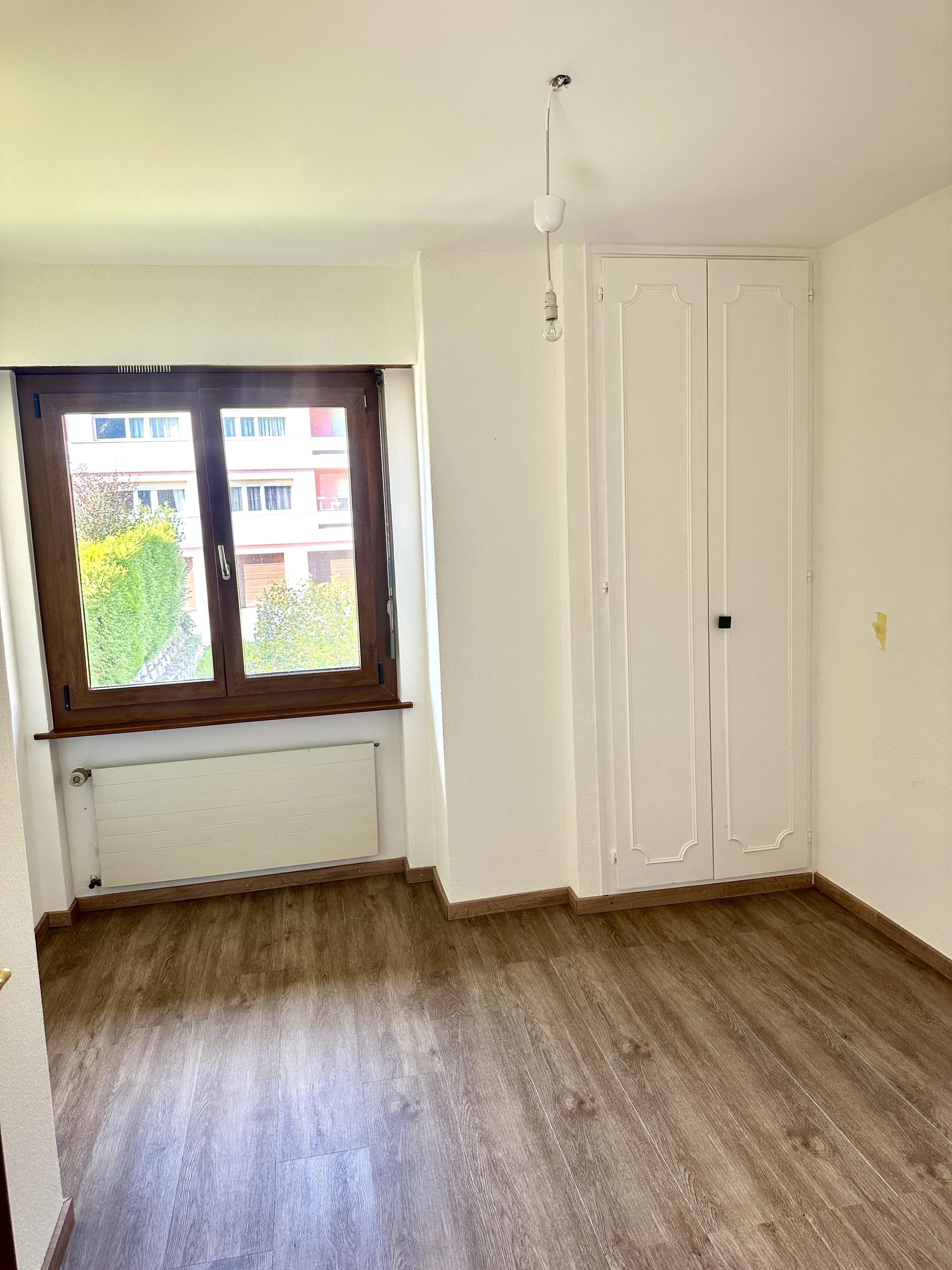 Helles, leeres Zimmer mit Fenster und Einbauschrank