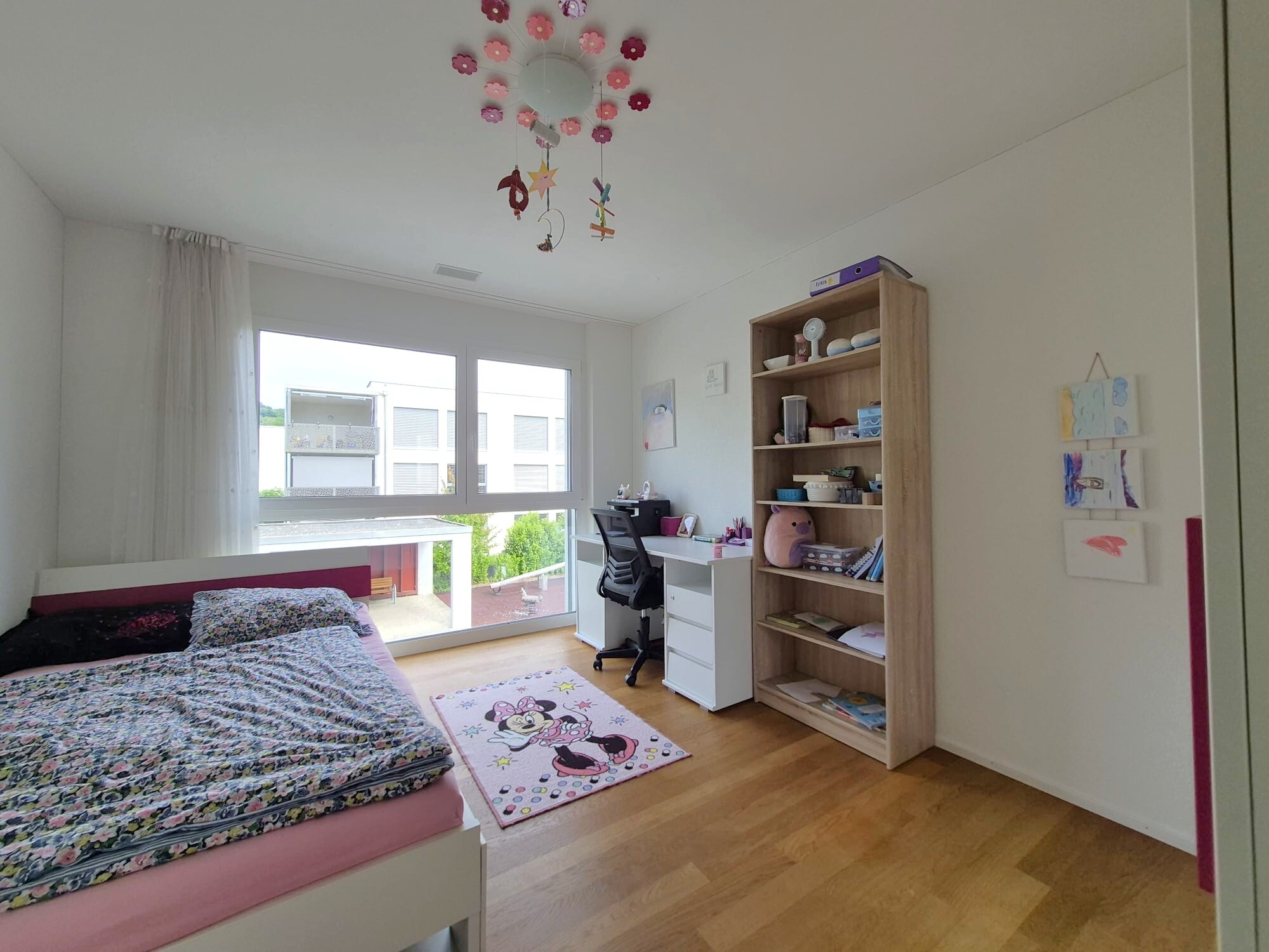 Helles Kinderzimmer mit Bett, Schreibtisch und Regal