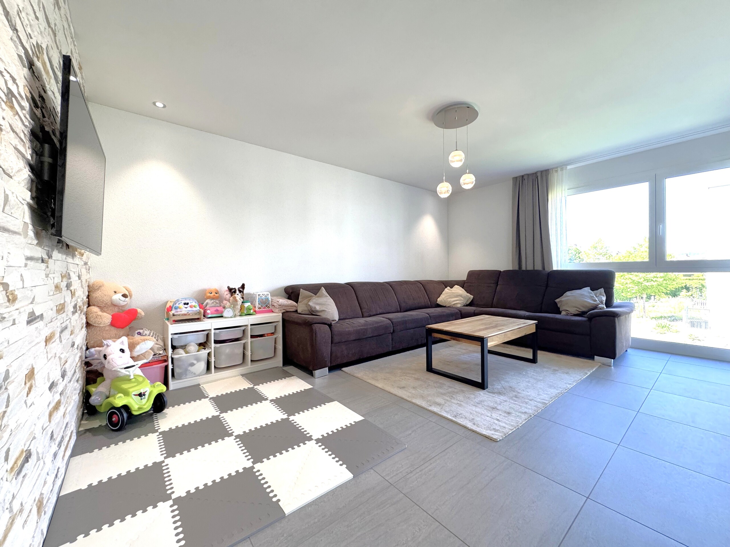 Helles Wohnzimmer mit Ecksofa und Kinderbereich