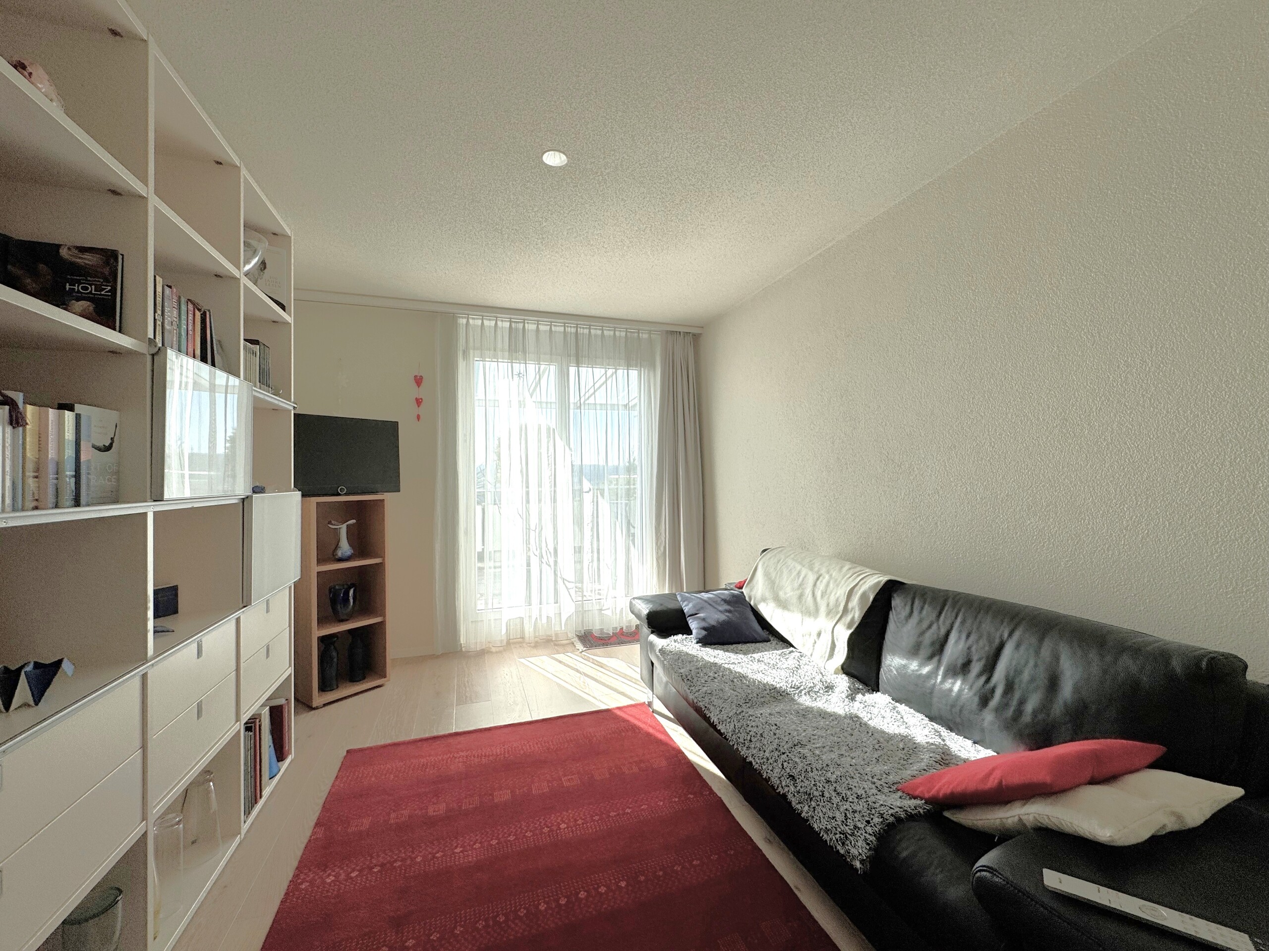 Helles Wohnzimmer mit Sofa und Regalwand