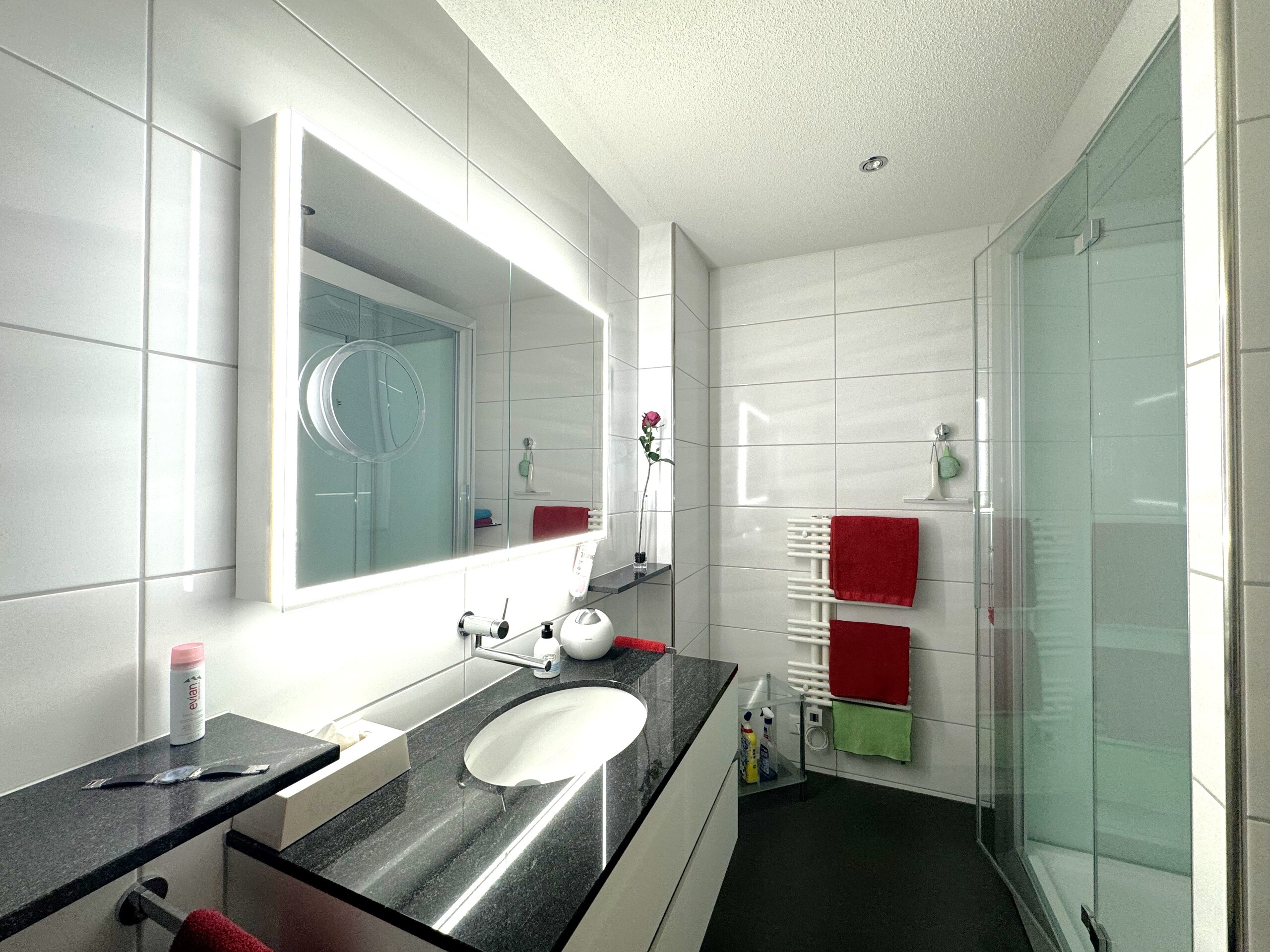 Modernes Badezimmer mit beleuchtetem Spiegel und Glasdusche