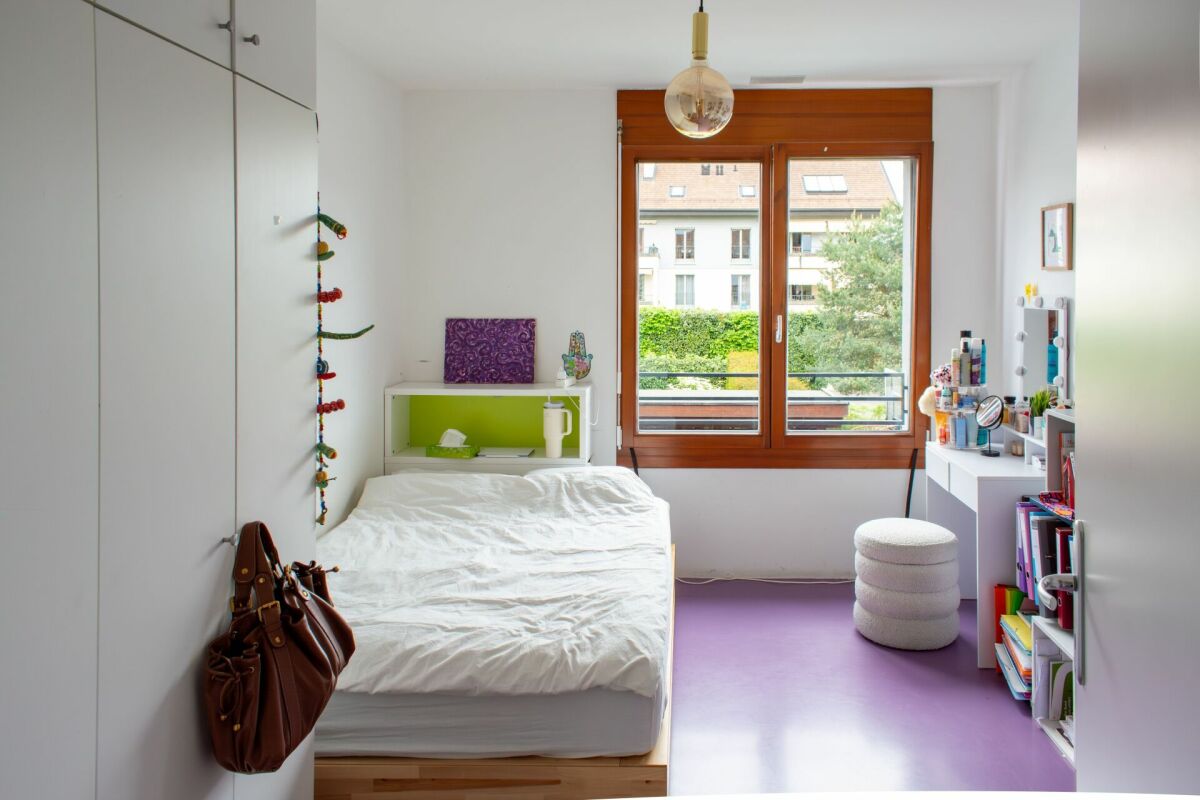 Helles Schlafzimmer mit großem Fenster und weißem Mobiliar