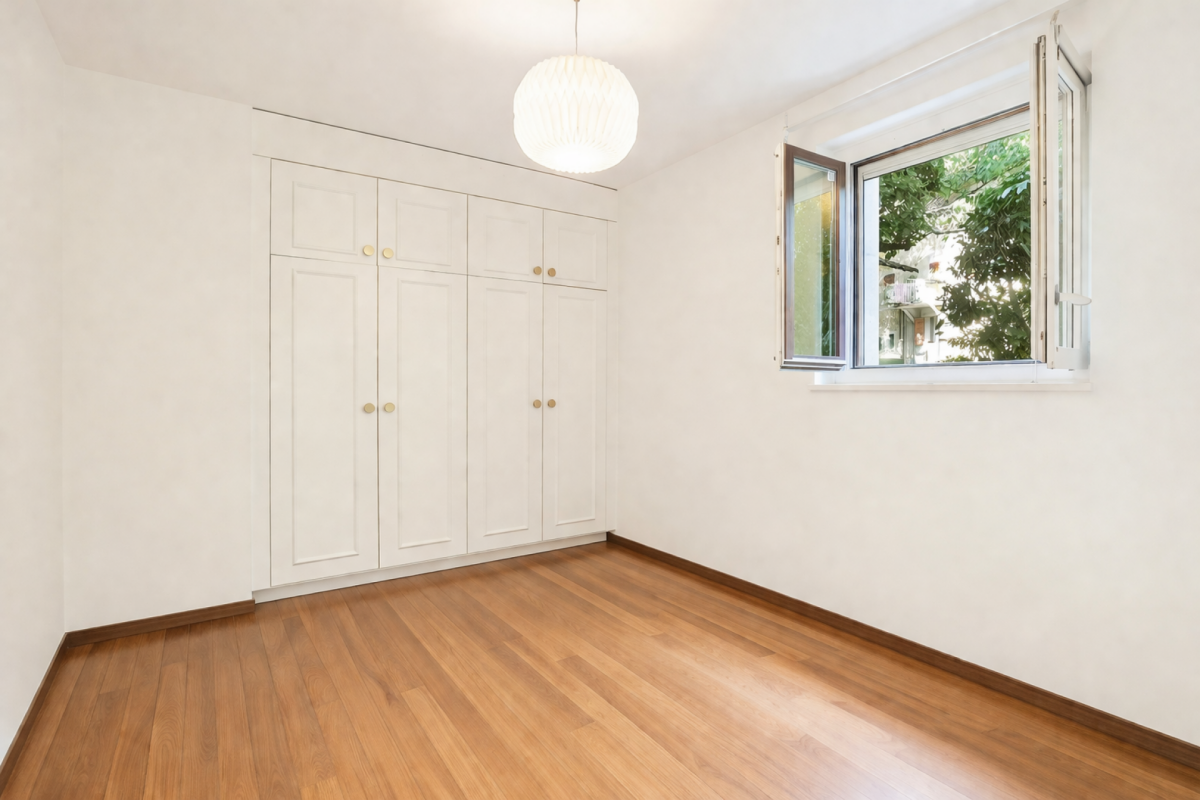 Helles, leeres Schlafzimmer mit Einbauschrank und Fenster