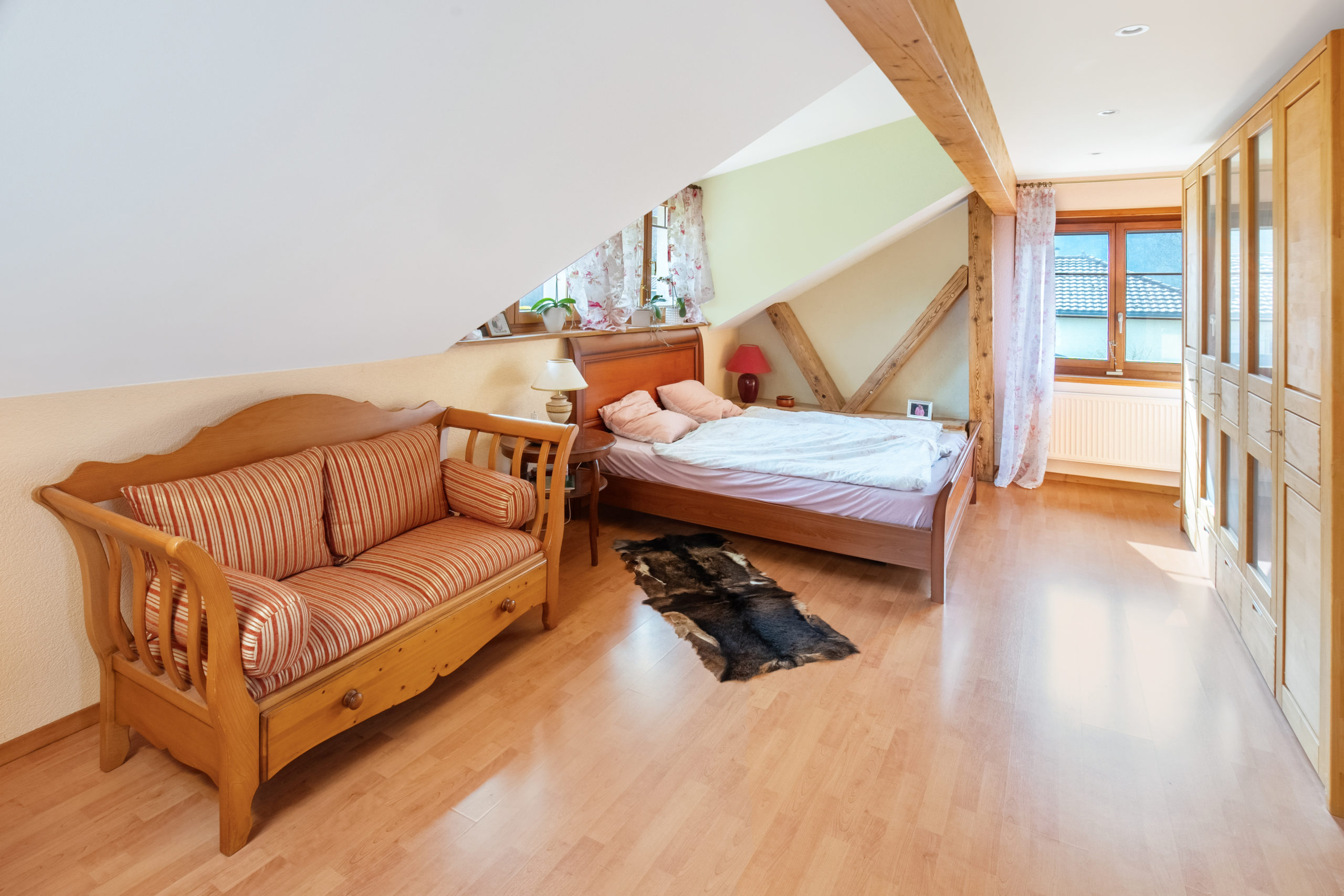 Helles Dachgeschoss-Schlafzimmer mit Holz- und Stoffmöblierung