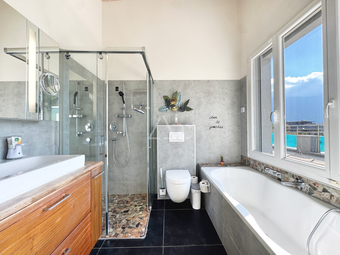 Modernes Badezimmer mit Dusche, Badewanne und Fensterblick