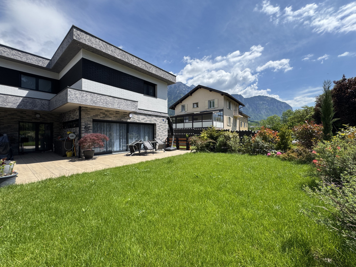 Moderne Gartenansicht mit Terrasse und Bergkulisse