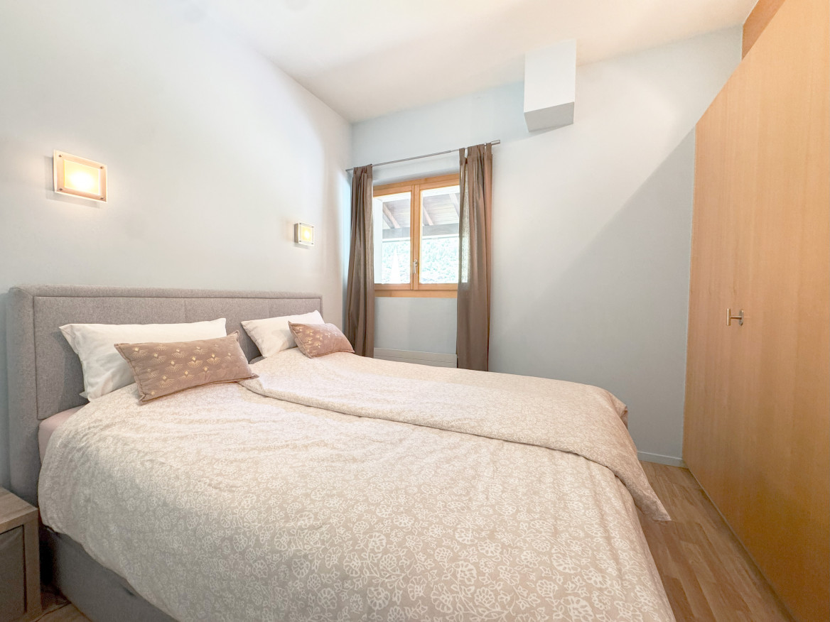 Helles Schlafzimmer mit Doppelbett und Holzfenster