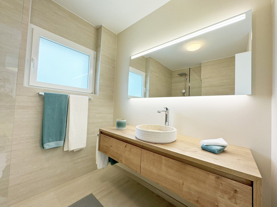 Modernes Badezimmer mit Holzoptik und Spiegelbeleuchtung