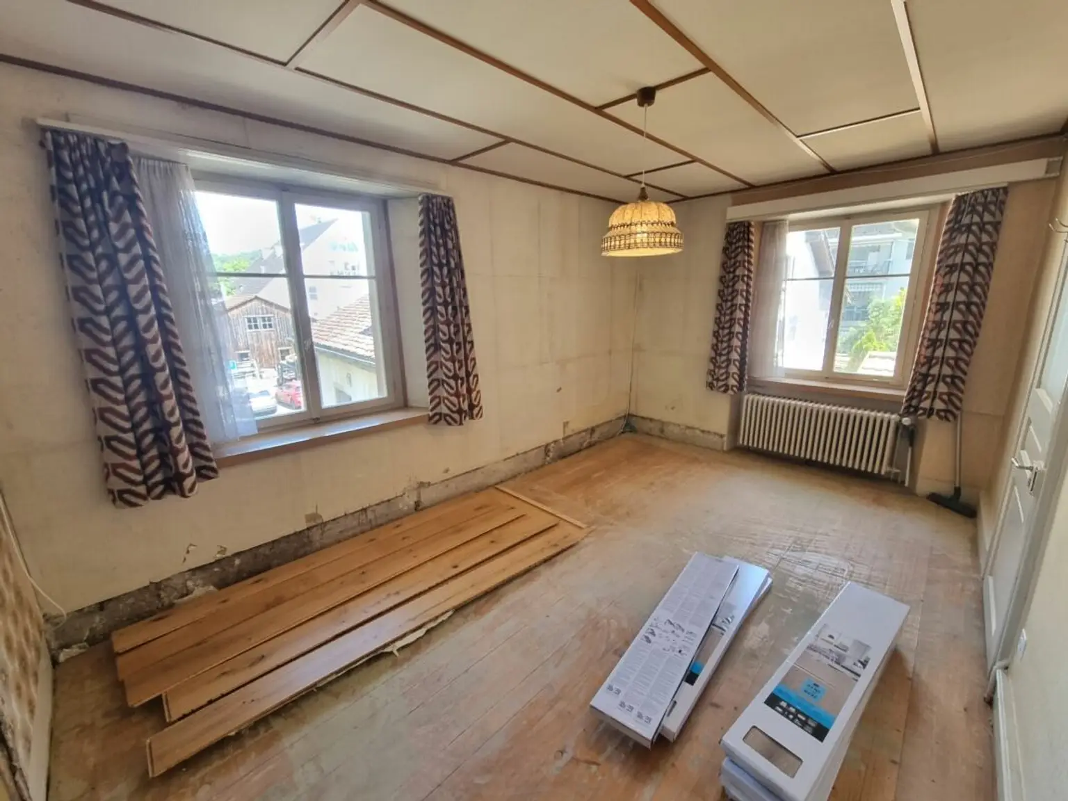 Renovierungsbedürftiges leeres Zimmer mit zwei Fenstern