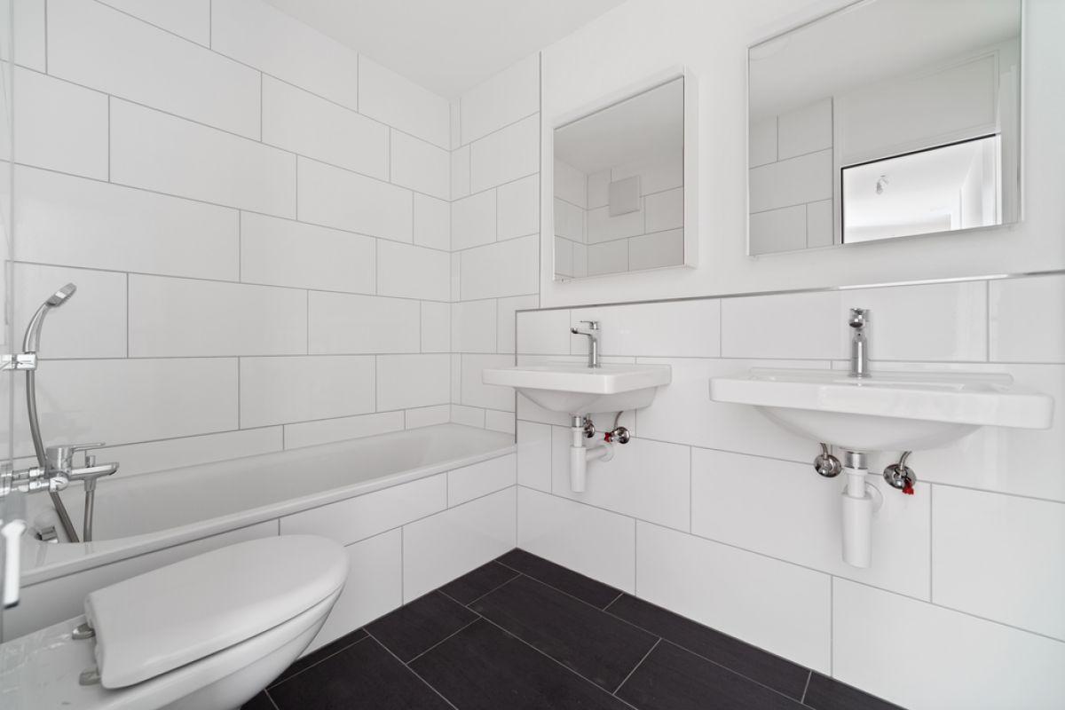 Modernes weißes Badezimmer mit Badewanne, zwei Waschbecken und WC