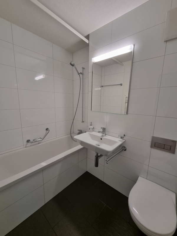 Kleines, modernes Badezimmer mit Badewanne und Wand-WC