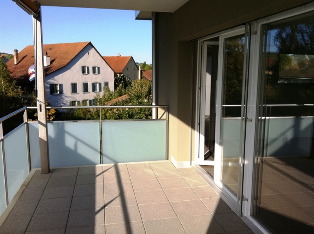 Balkon mit Glasgeländer und Blick auf Wohnhäuser