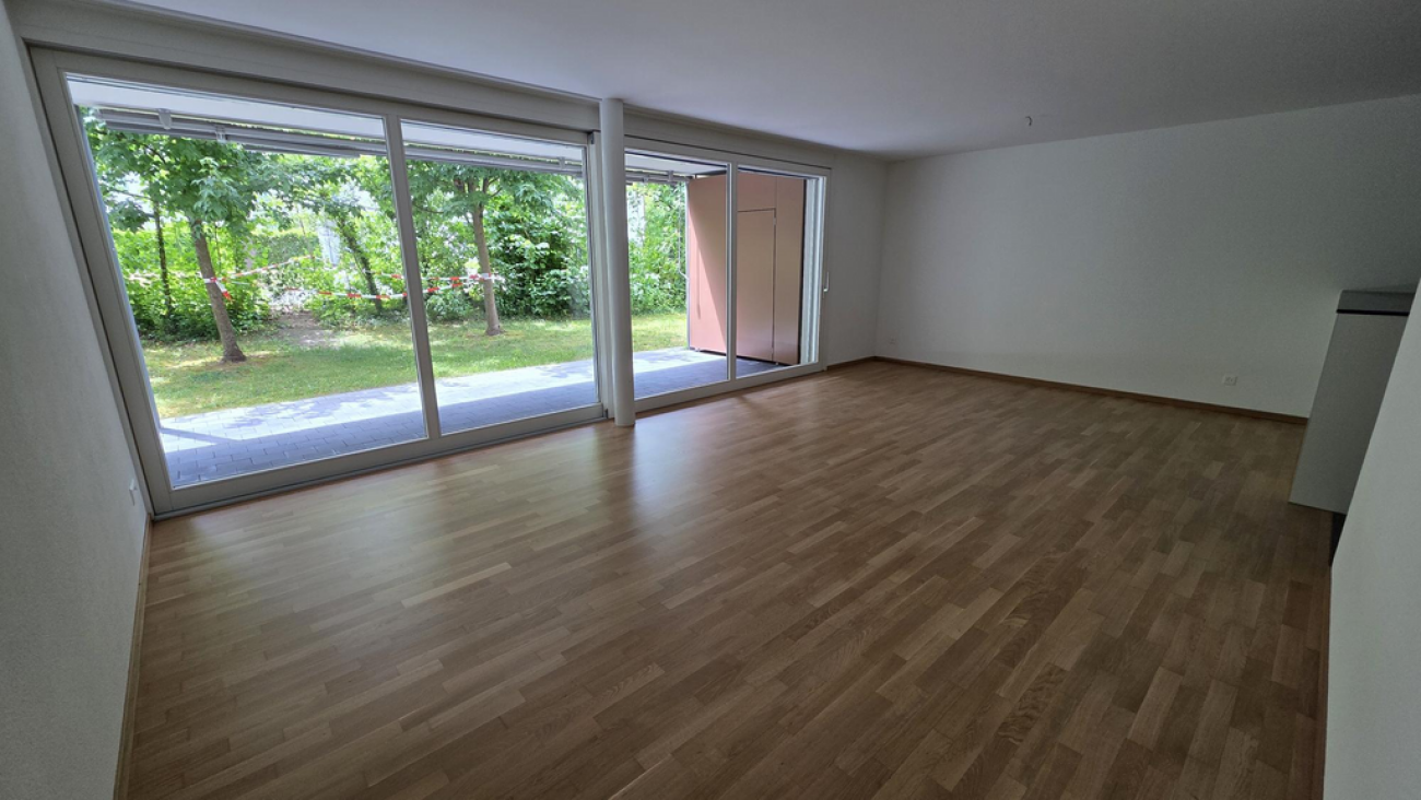 Leerer Wohnraum mit großen Schiebetüren zum Garten