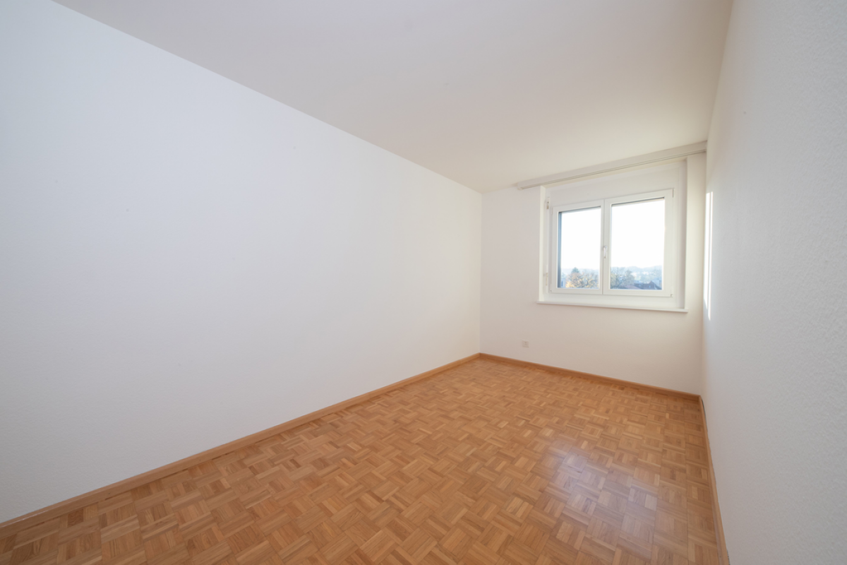 Leerer heller Raum mit Parkettboden und Fenster
