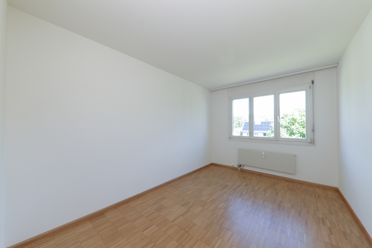 Helles, leeres Zimmer mit Fenster und Heizkörper