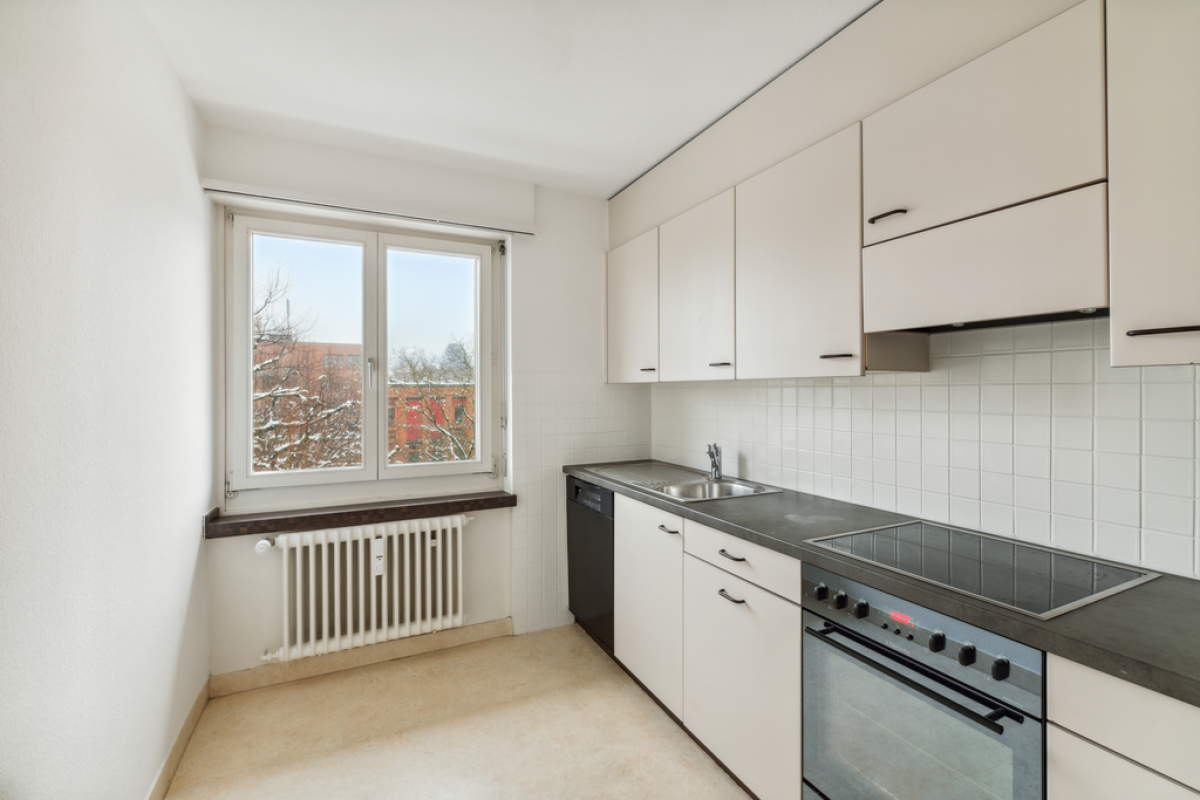 Helle, schmale Küche mit Fenster und weißen Fronten