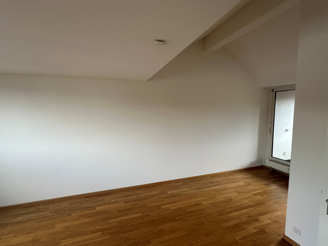 Leerer Raum mit Holzparkett und schräger Decke