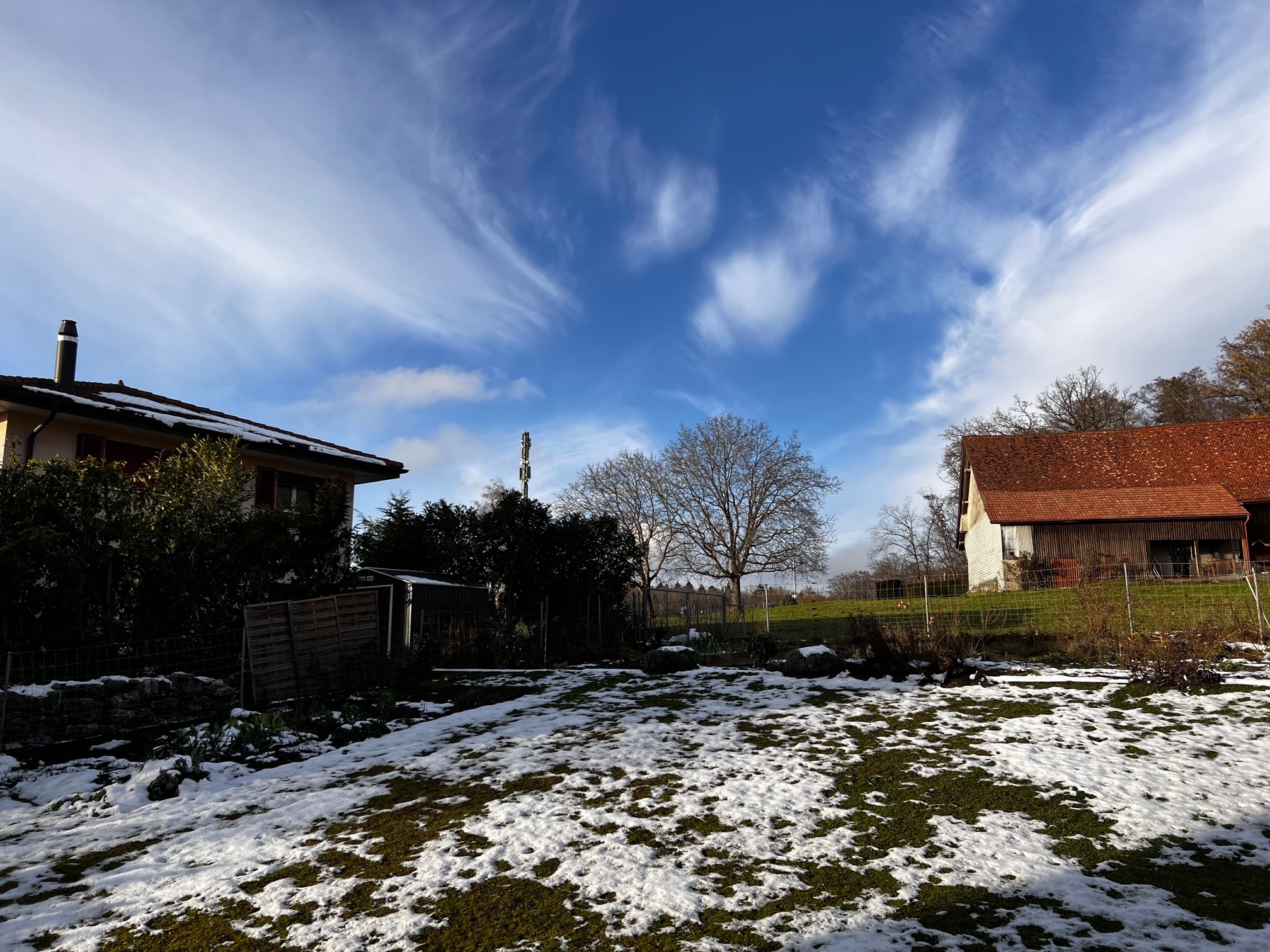 Ländlicher Garten mit Schnee und benachbarten Gebäuden