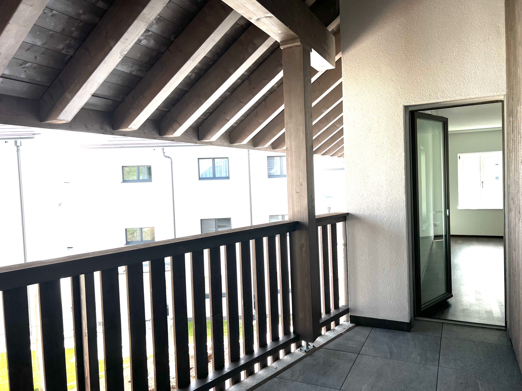 Balkon mit Holzgeländer und Blick in einen Innenhof