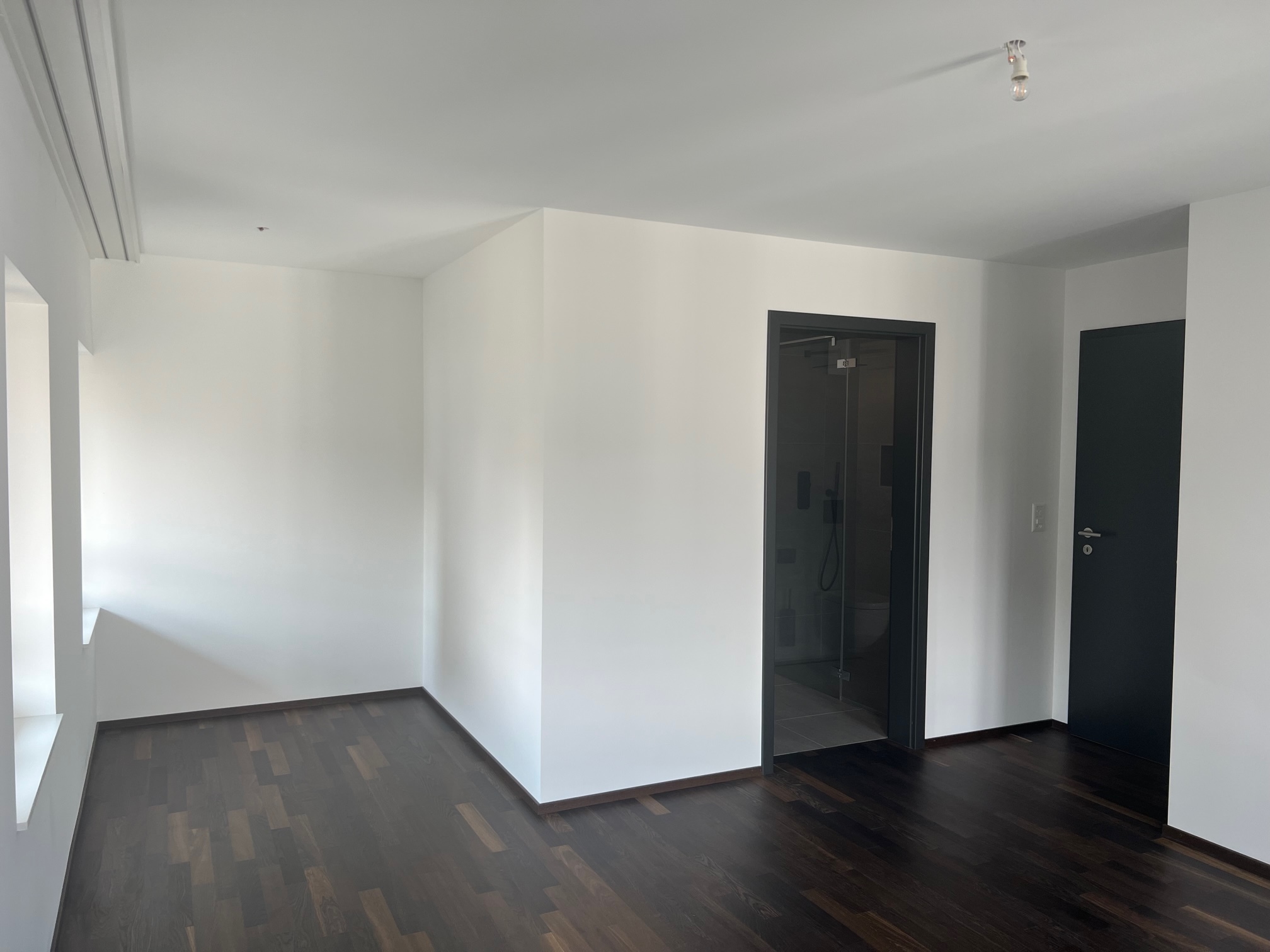 Modernes, leeres Zimmer mit dunklem Holzboden