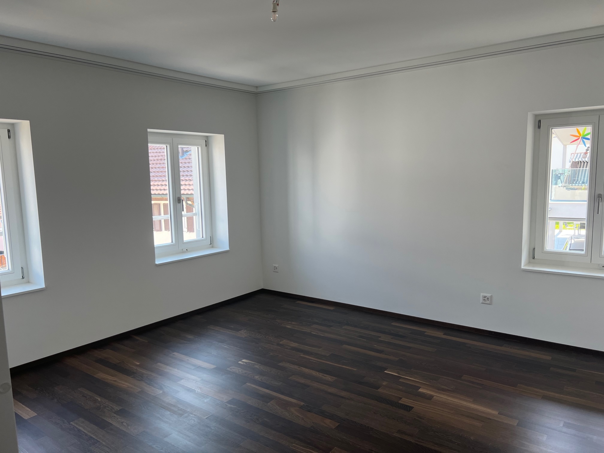 Leerer, frisch renovierter Raum mit dunklem Holzboden