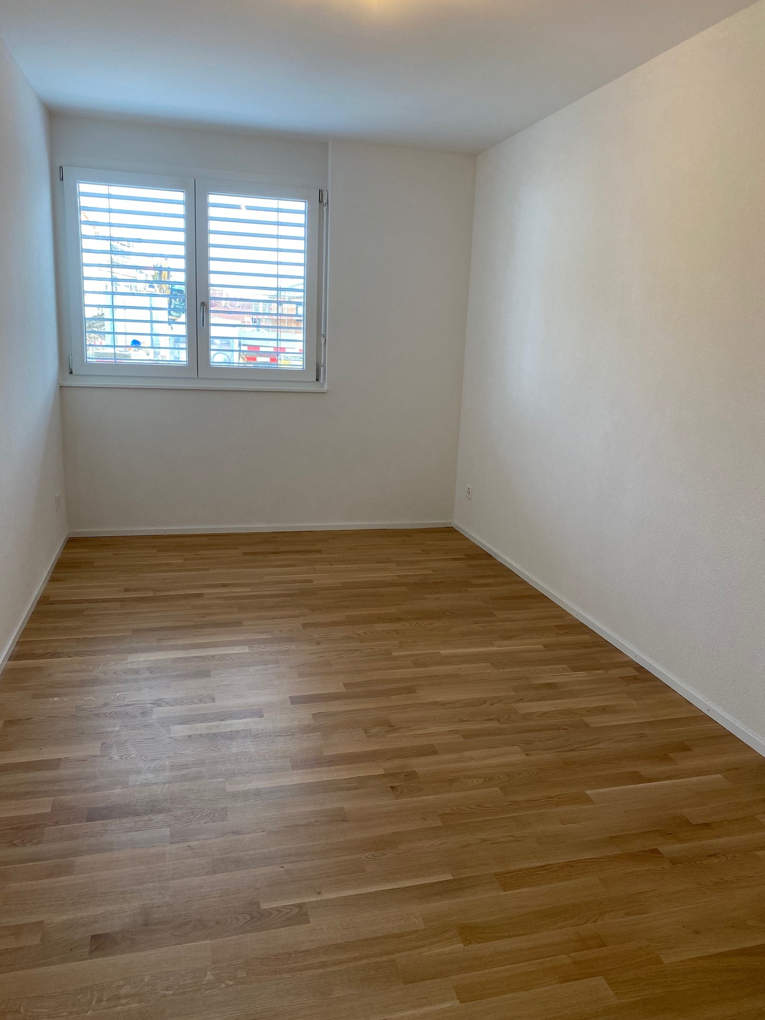 Leerer heller Raum mit Holzfußboden und Fenster