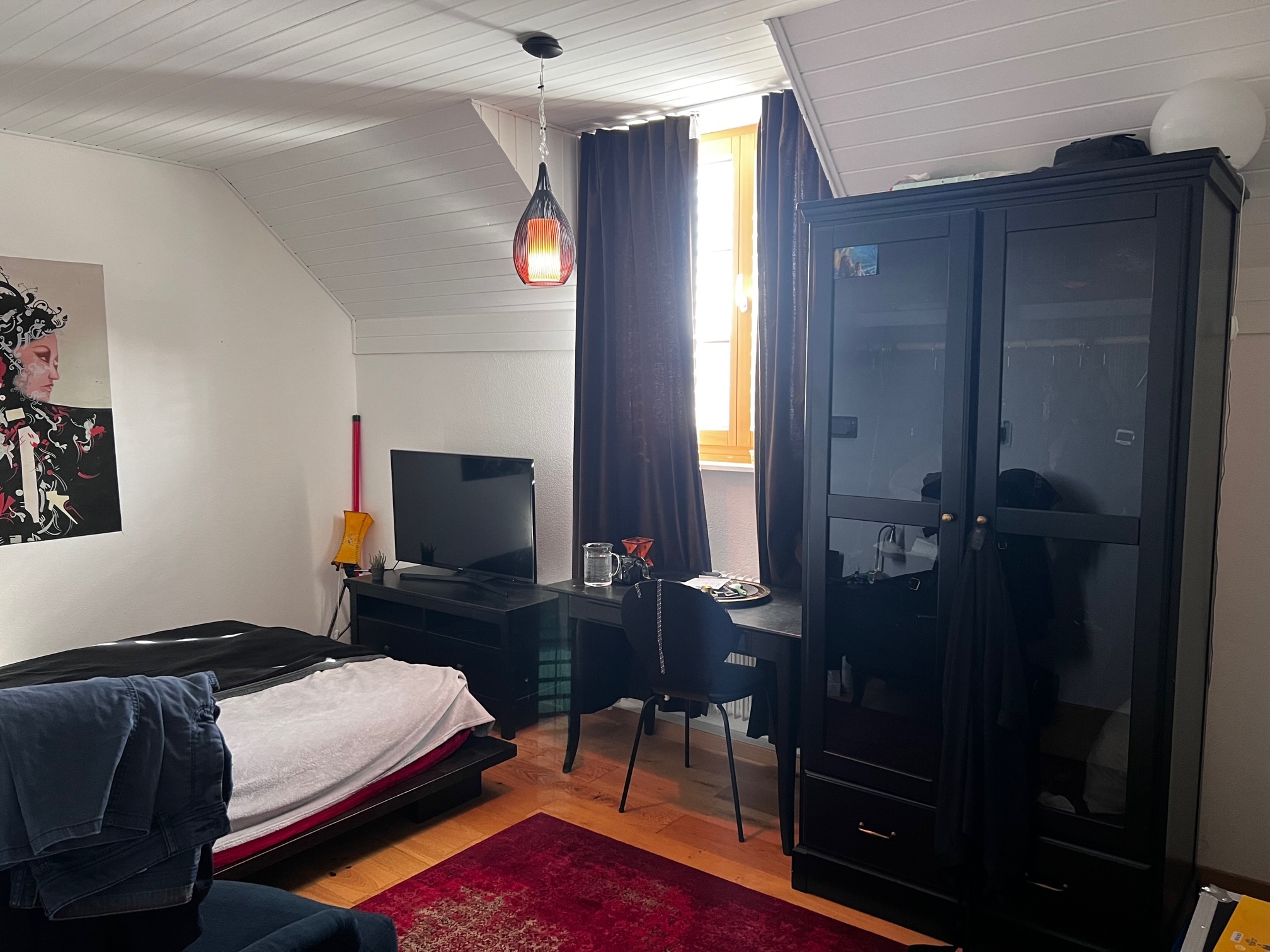 Dachzimmer mit Bett und Arbeitsbereich