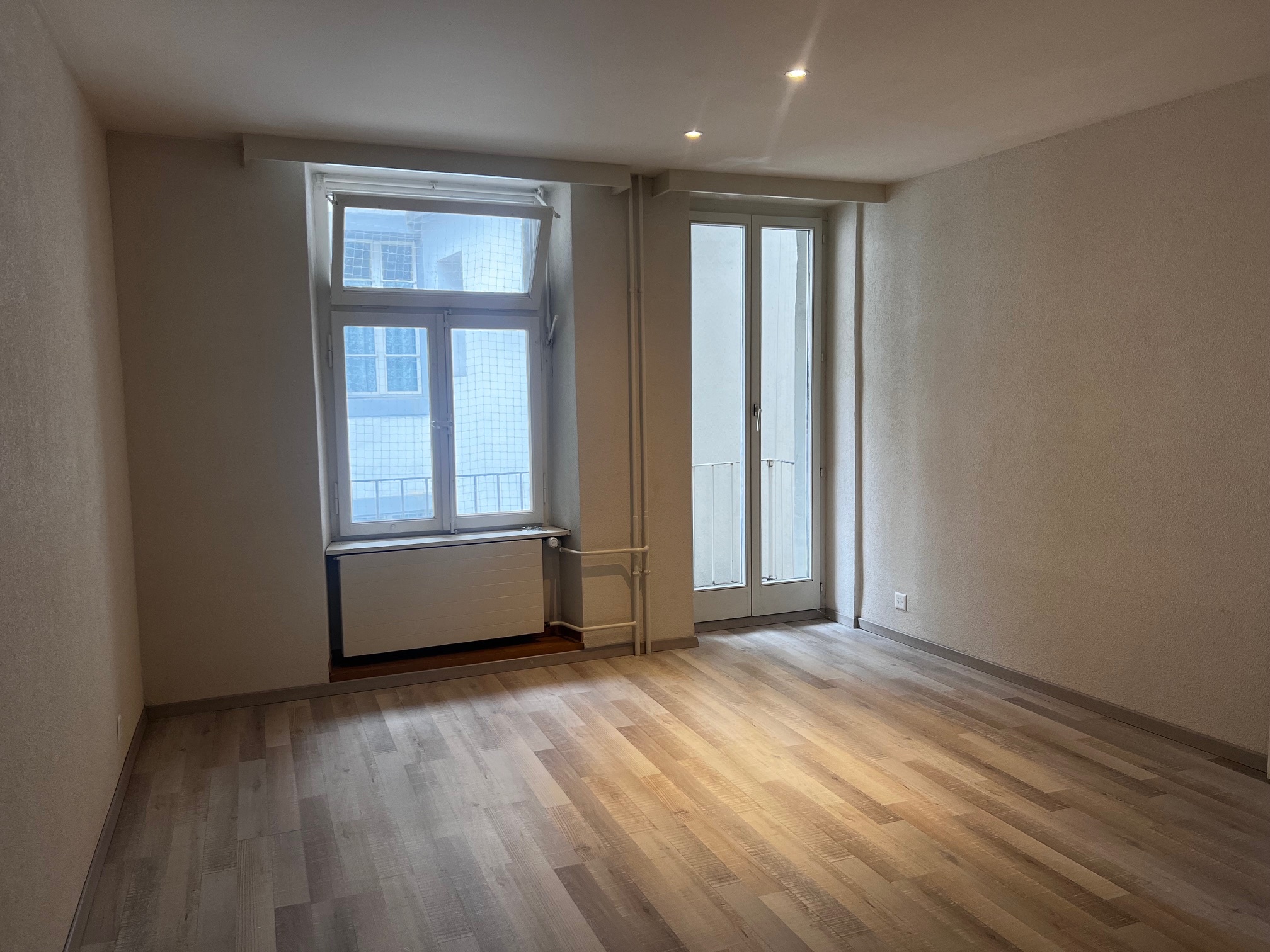 Leerer Wohnraum mit Fenstern und Balkontür