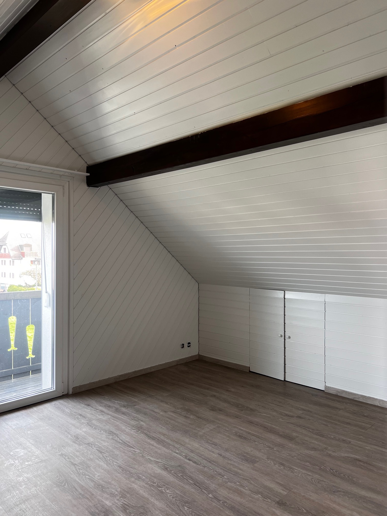 Dachgeschosszimmer mit Dachschräge und Balkonzugang