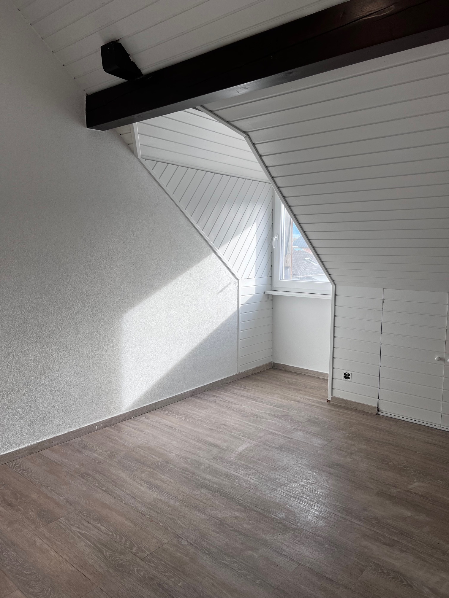 Dachgeschossraum mit Dachfenster und Holzoptikboden