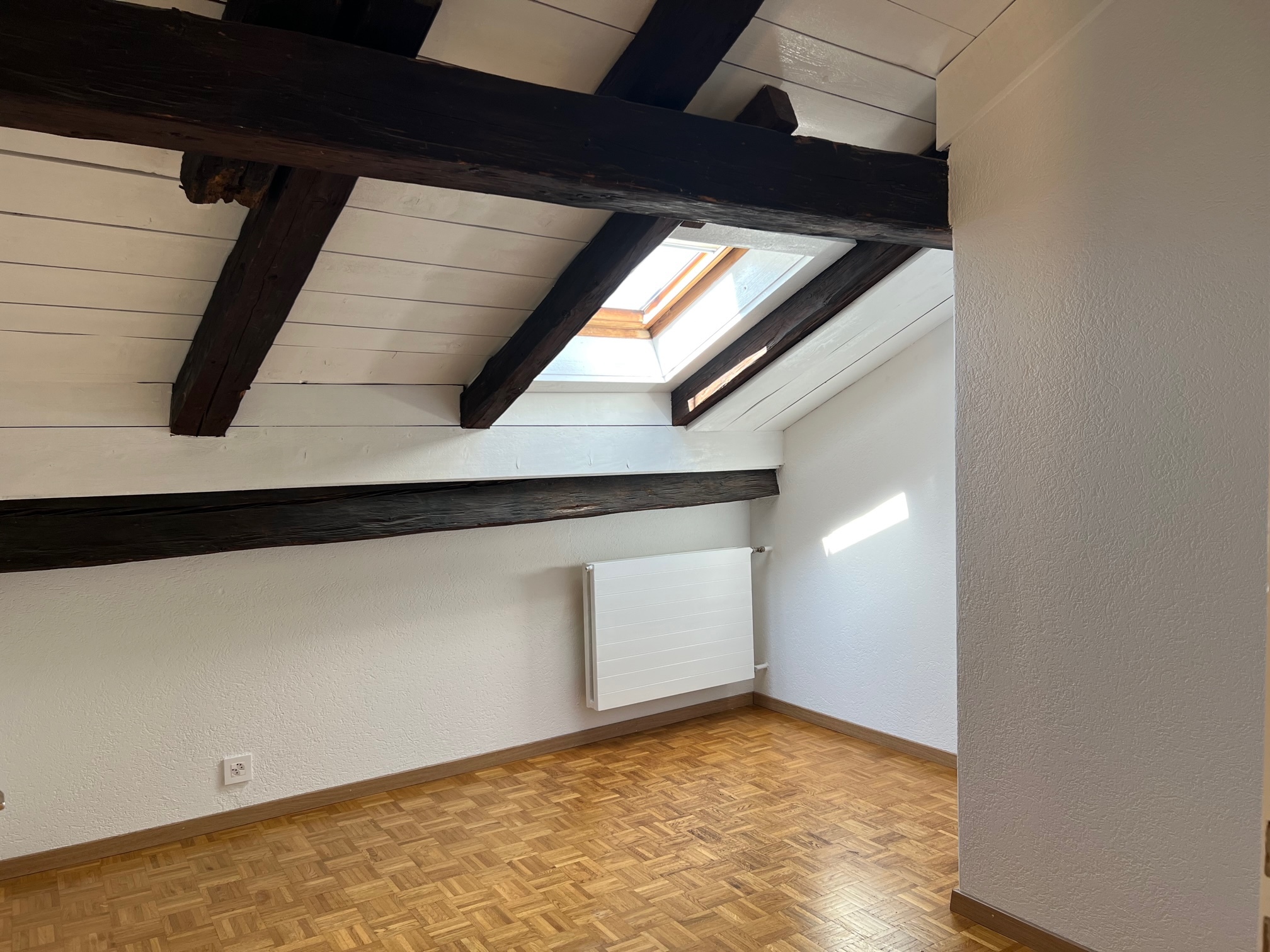 Dachzimmer mit sichtbaren Holzbalken